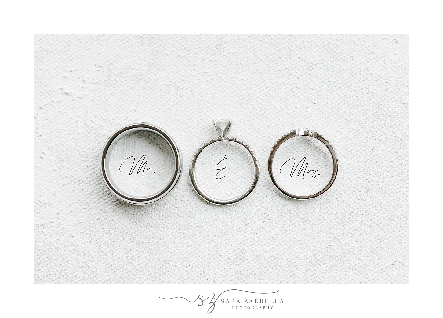 silver wedding rings on Mr and Mrs on white backdrop 