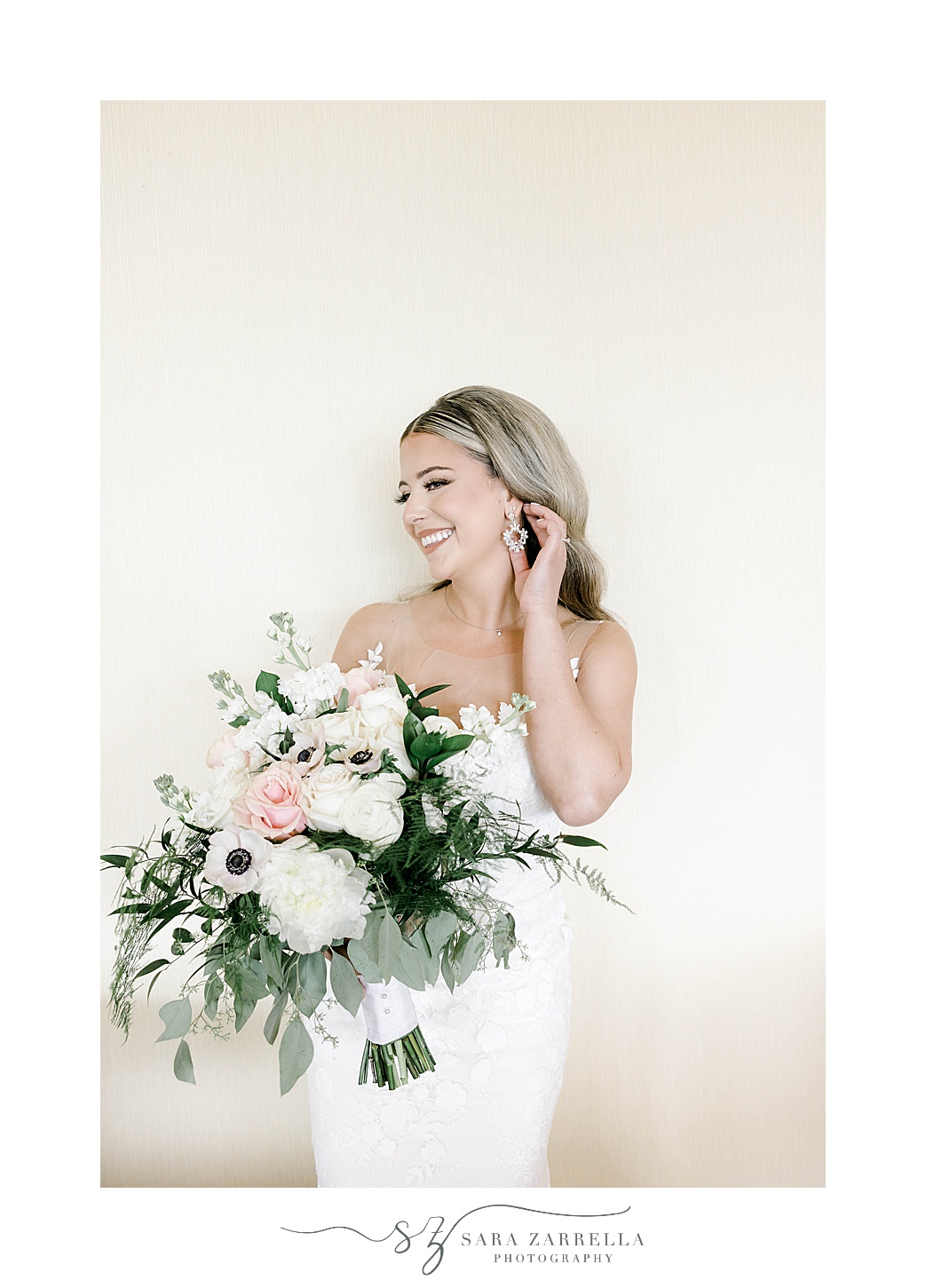 bride pushes hair behind ear holding bouquet of pink and white flowers