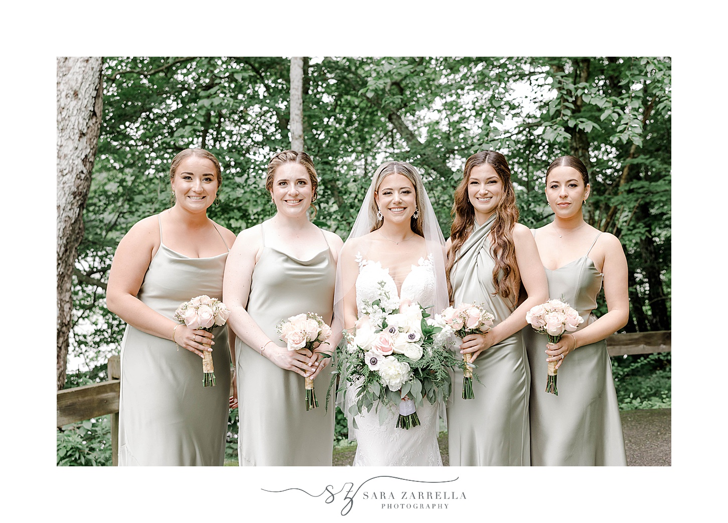 bride stands with bridesmaids in pale green gowns 