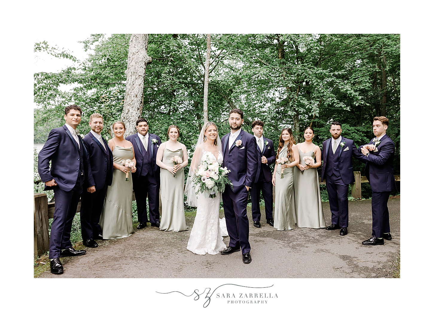 bride and groom hug in front of wedding party in mint green gown and navy suits 