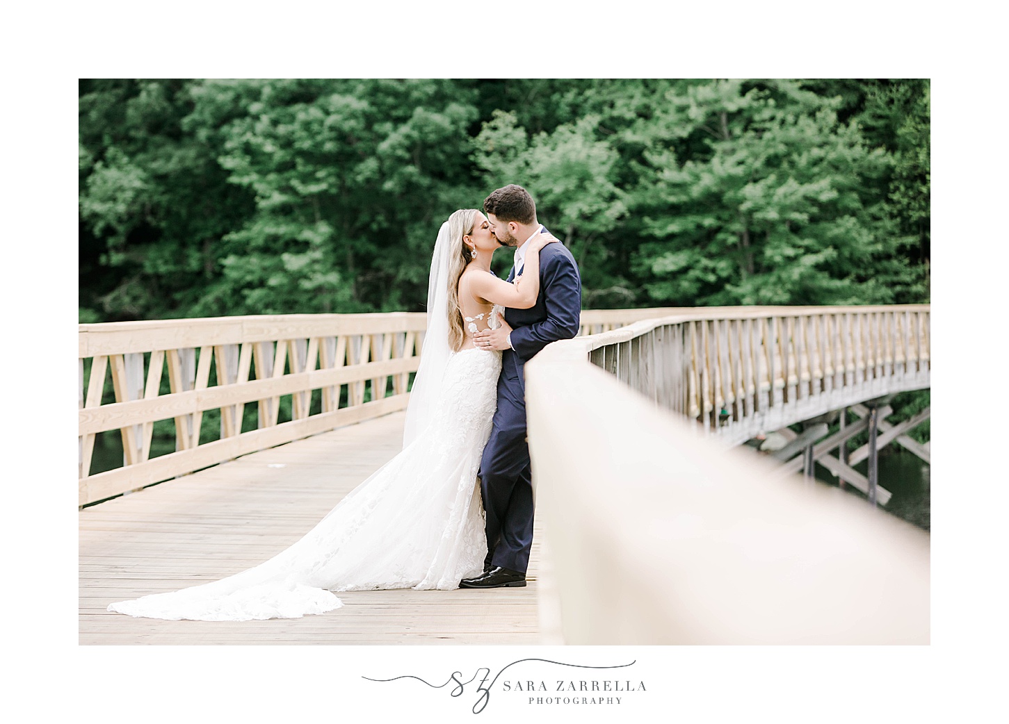 bride leans to kiss groom against wooden railing at the Lake of Isles