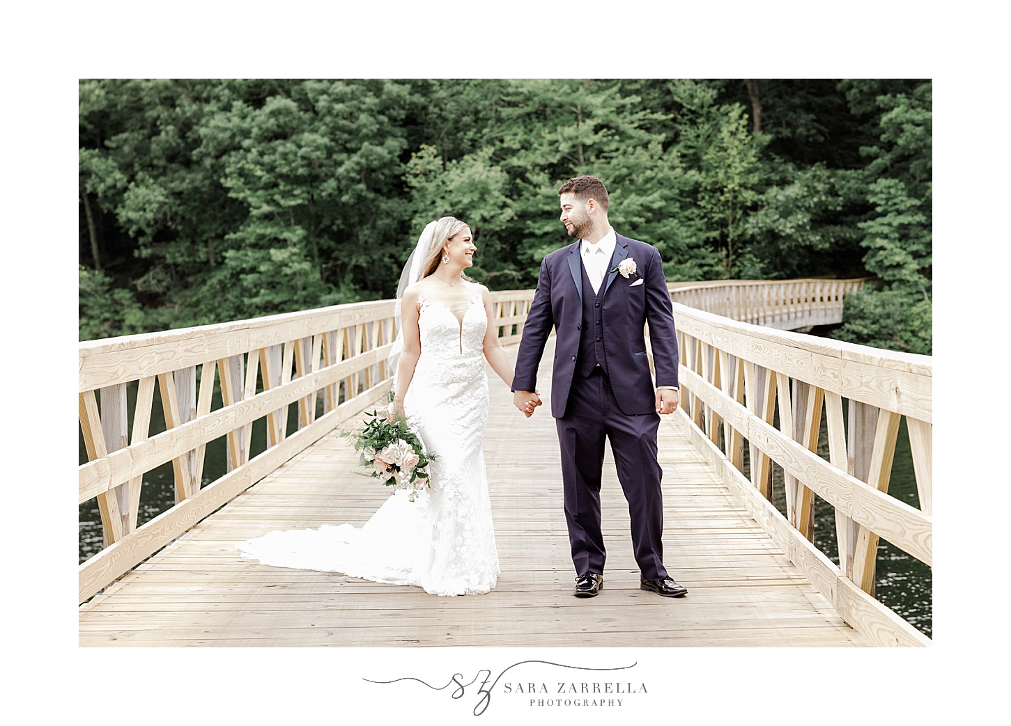 newlyweds hold hands standing on wooden pathway at Lake of Isles