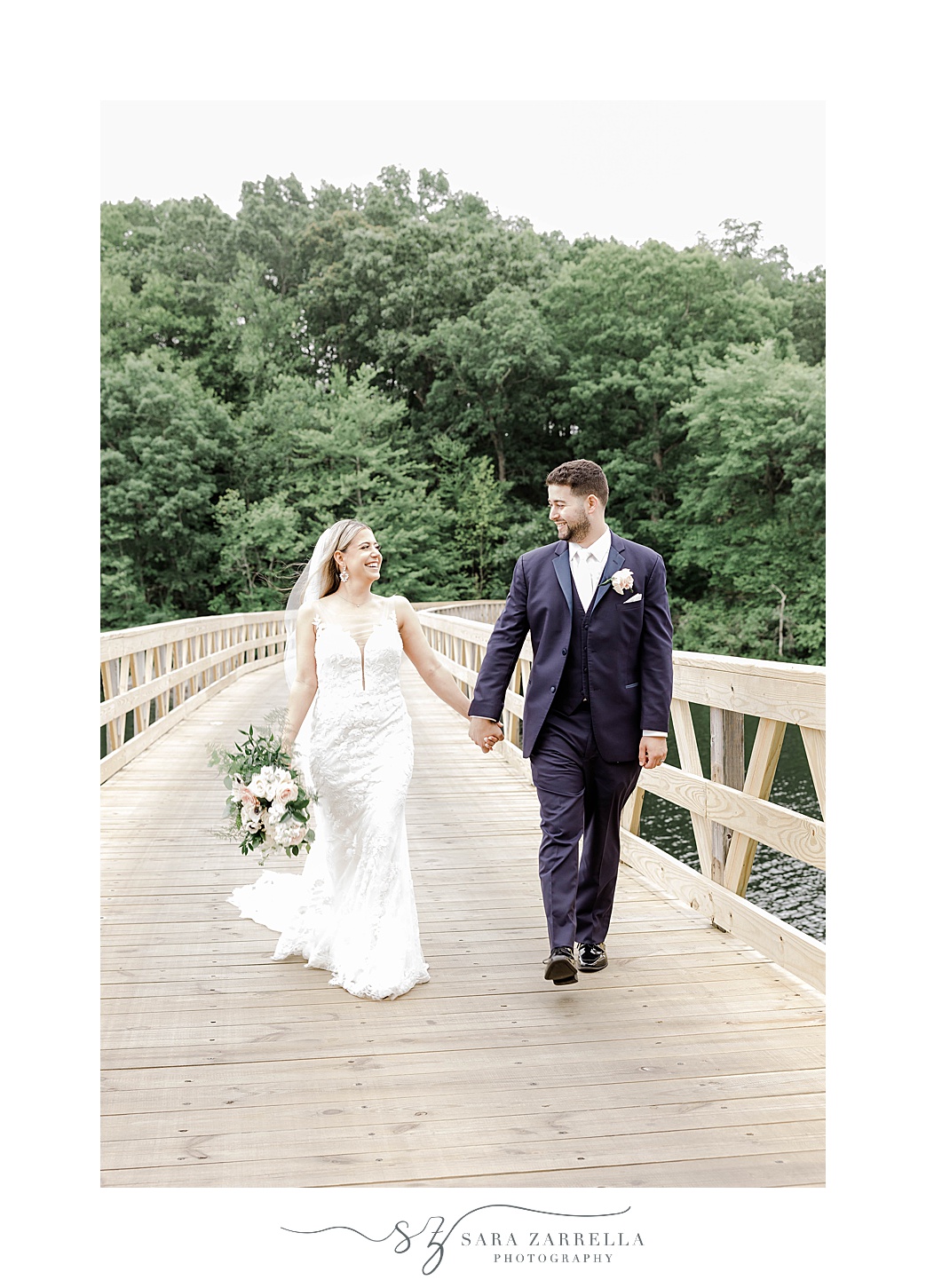 bride and groom hold hands walking together on wooden path at the Lake of Isles