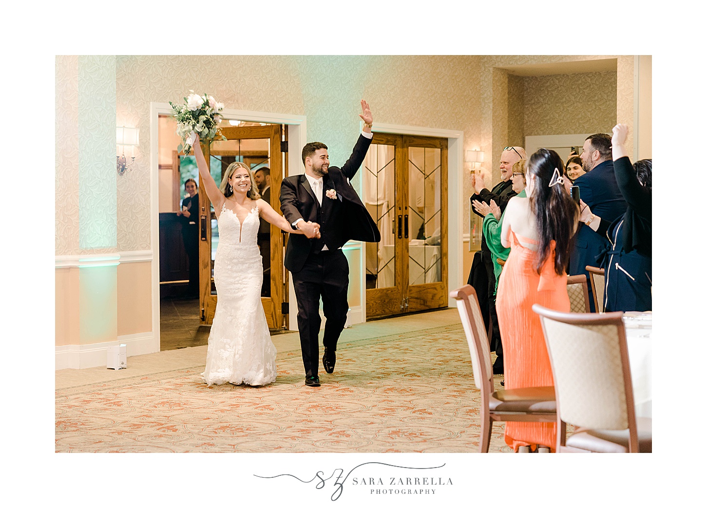 newlyweds cheer and wave walking into wedding reception at Lake of Isles