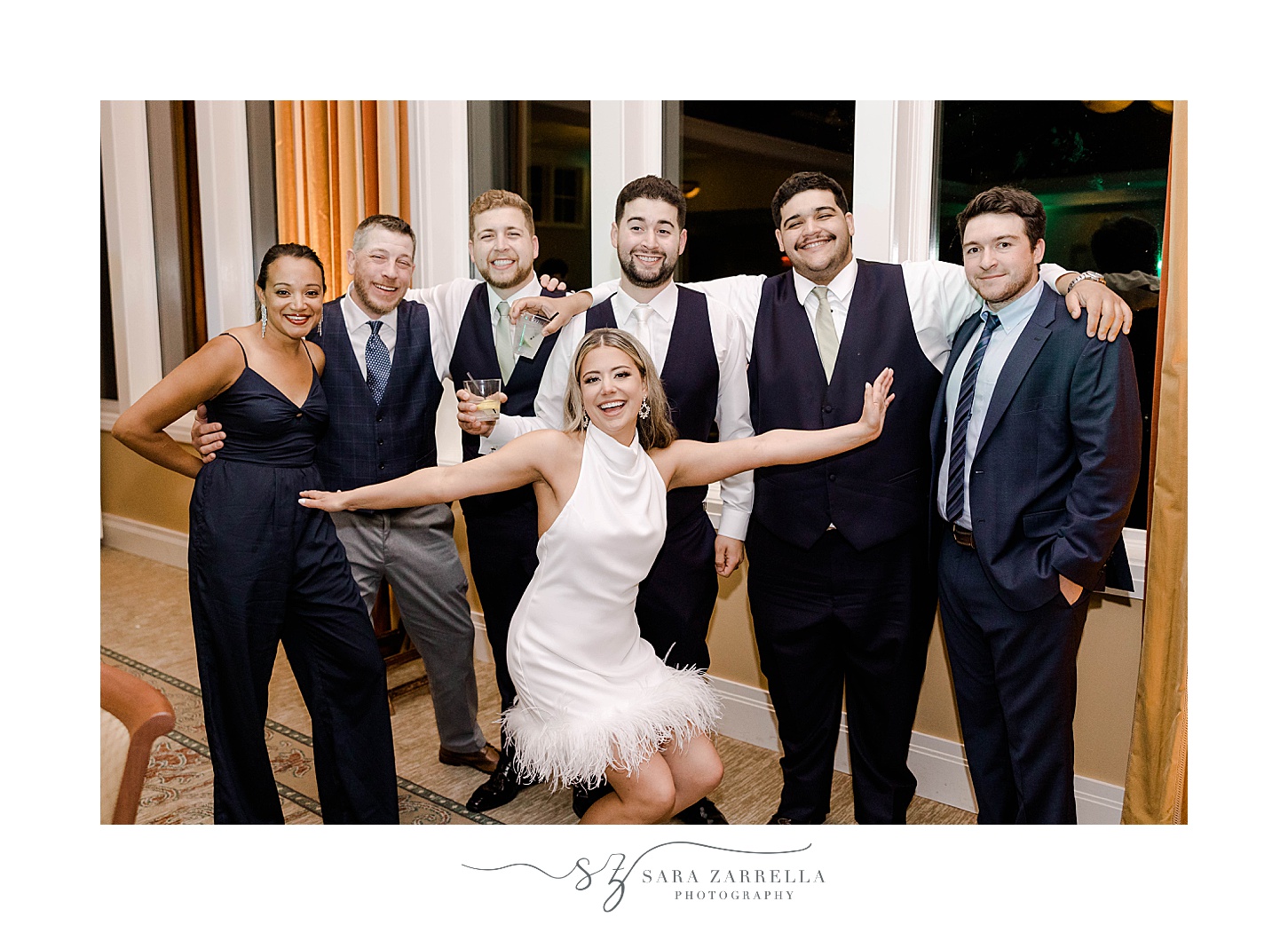 bride poses with groomsmen in party dress with fringe 