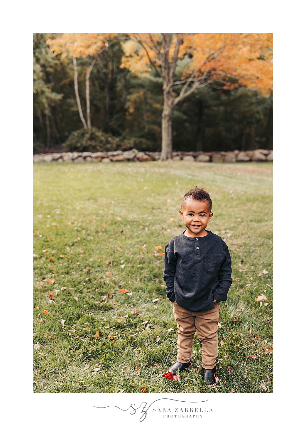 toddler in blue sweater stands with hands in pocket of khaki pants