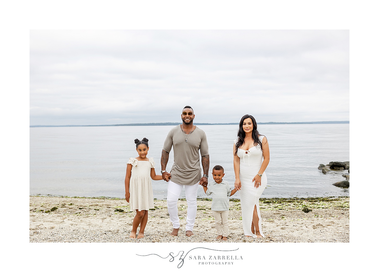 family of four holds hands walking on beach during Beach mini sessions