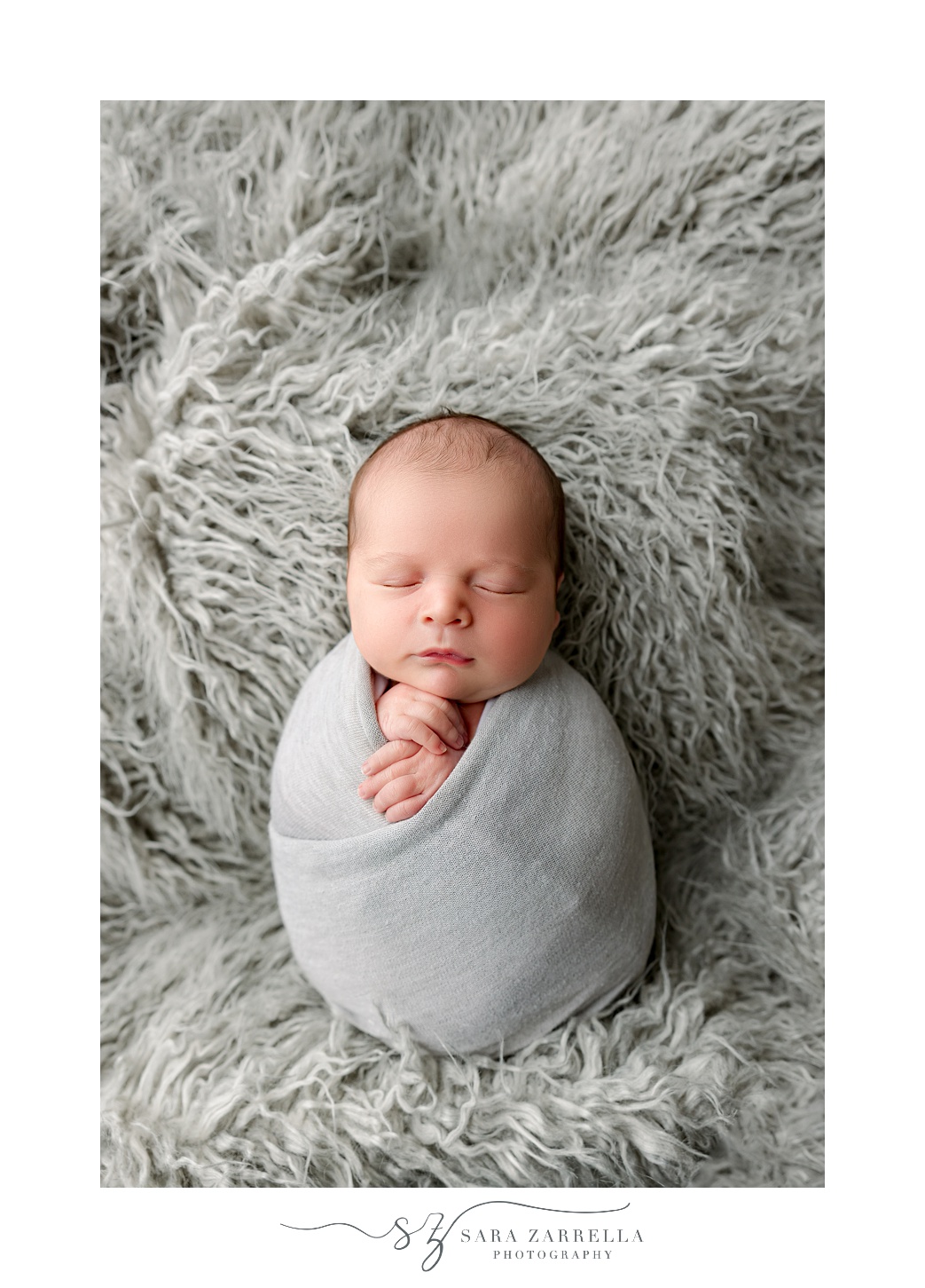 newborn baby boy sits in grey wrap on fuzzy grey blanket during newborn session with Rhode Island newborn and family photographer Sara Zarrella Photography