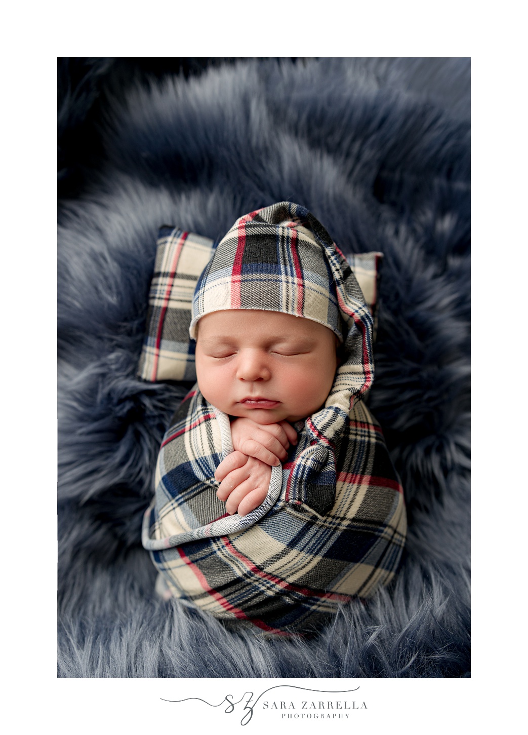 baby lays on fuzzy blue blanket in plaid wrap during newborn session with Rhode Island newborn and family photographer Sara Zarrella Photography