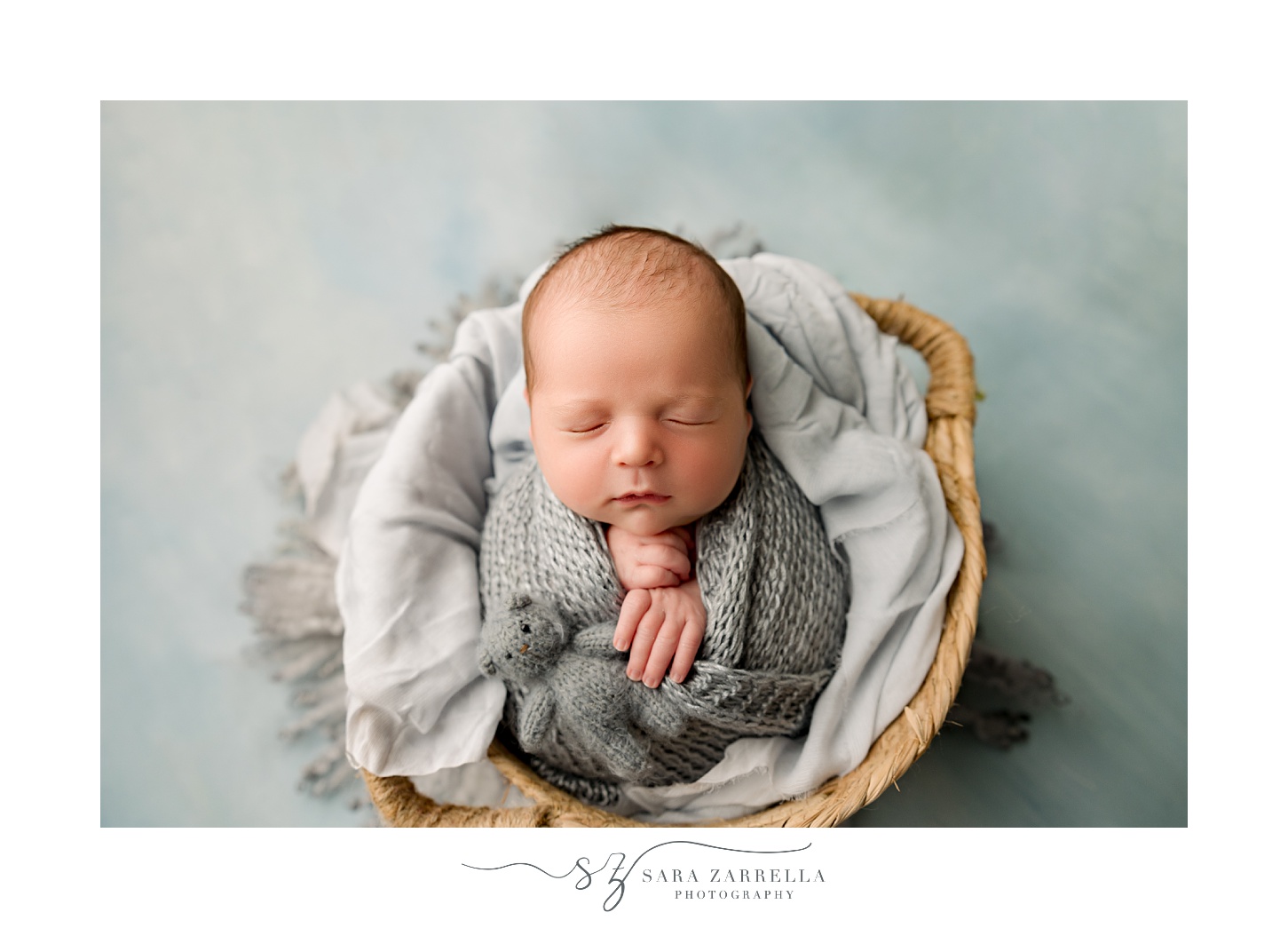 boy lays in basket with grey blanket during newborn session with Rhode Island newborn and family photographer Sara Zarrella Photography