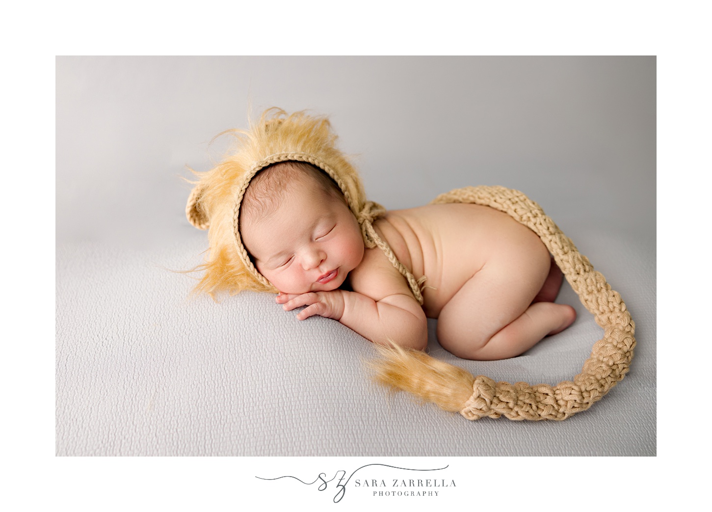 baby in lion outfit lays on grey blanket during newborn session with Rhode Island newborn and family photographer Sara Zarrella Photography