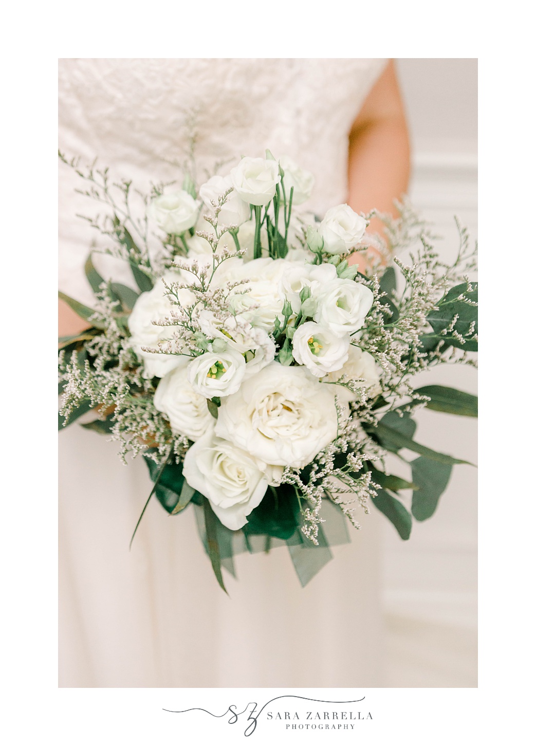 bride's all white bouquet with baby's breath and green leaves 