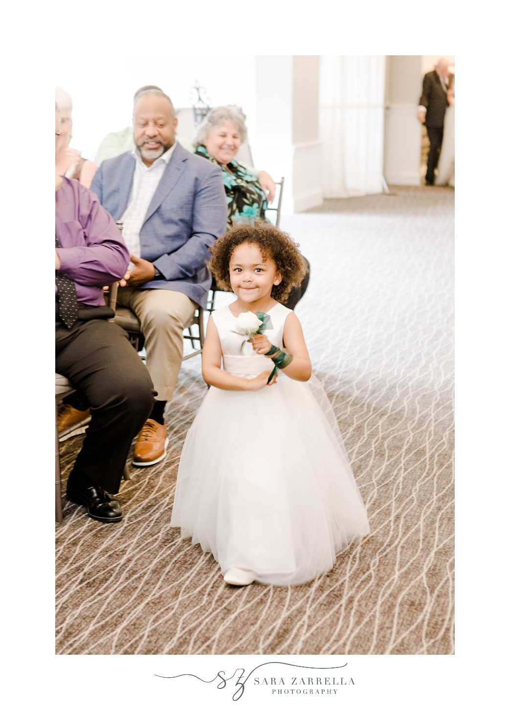 flower girl in white dress walks down aisle in ballroom at Harbor Lights