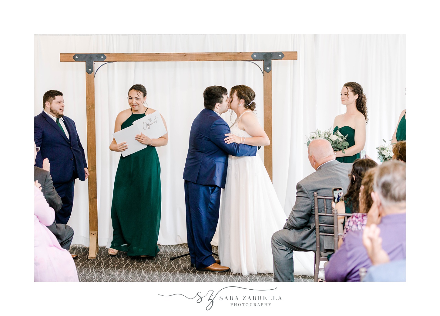 groom in navy suit kisses bride during ceremony at Harbor Lights