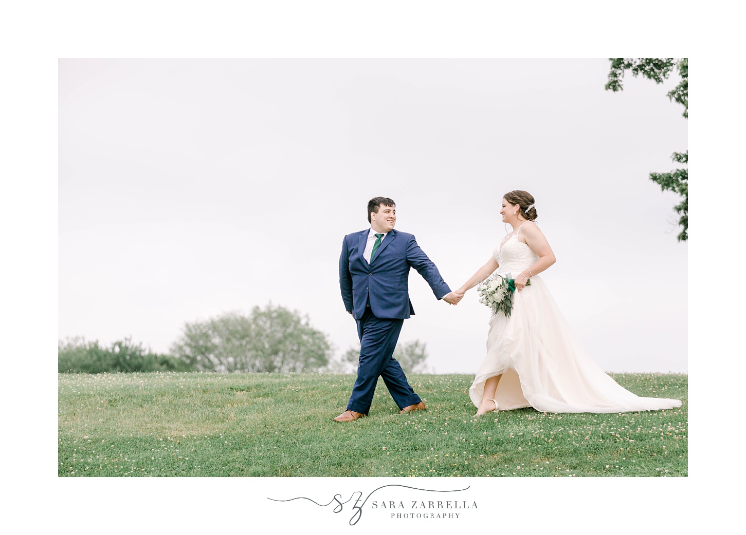 groom leads bride across hill at Harbor Lights