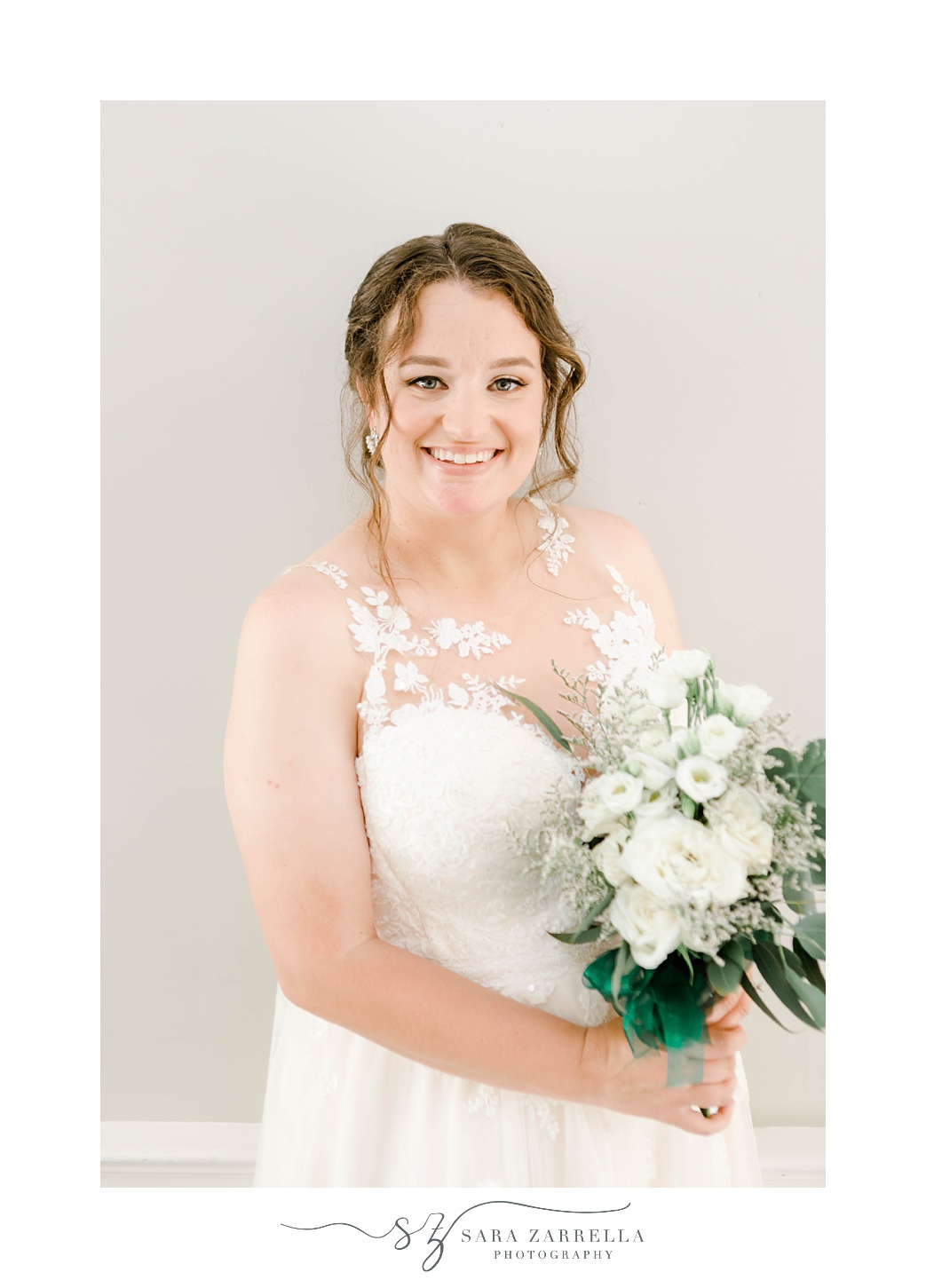 bride smiles holding bouquet of white bouquets with baby's breath 