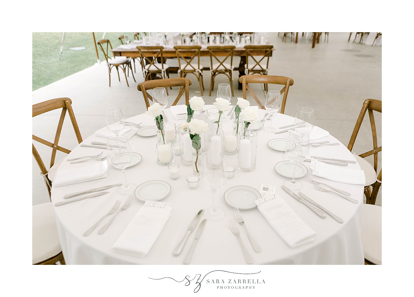 wedding reception with circular table with white napkins, roses, and place settings 