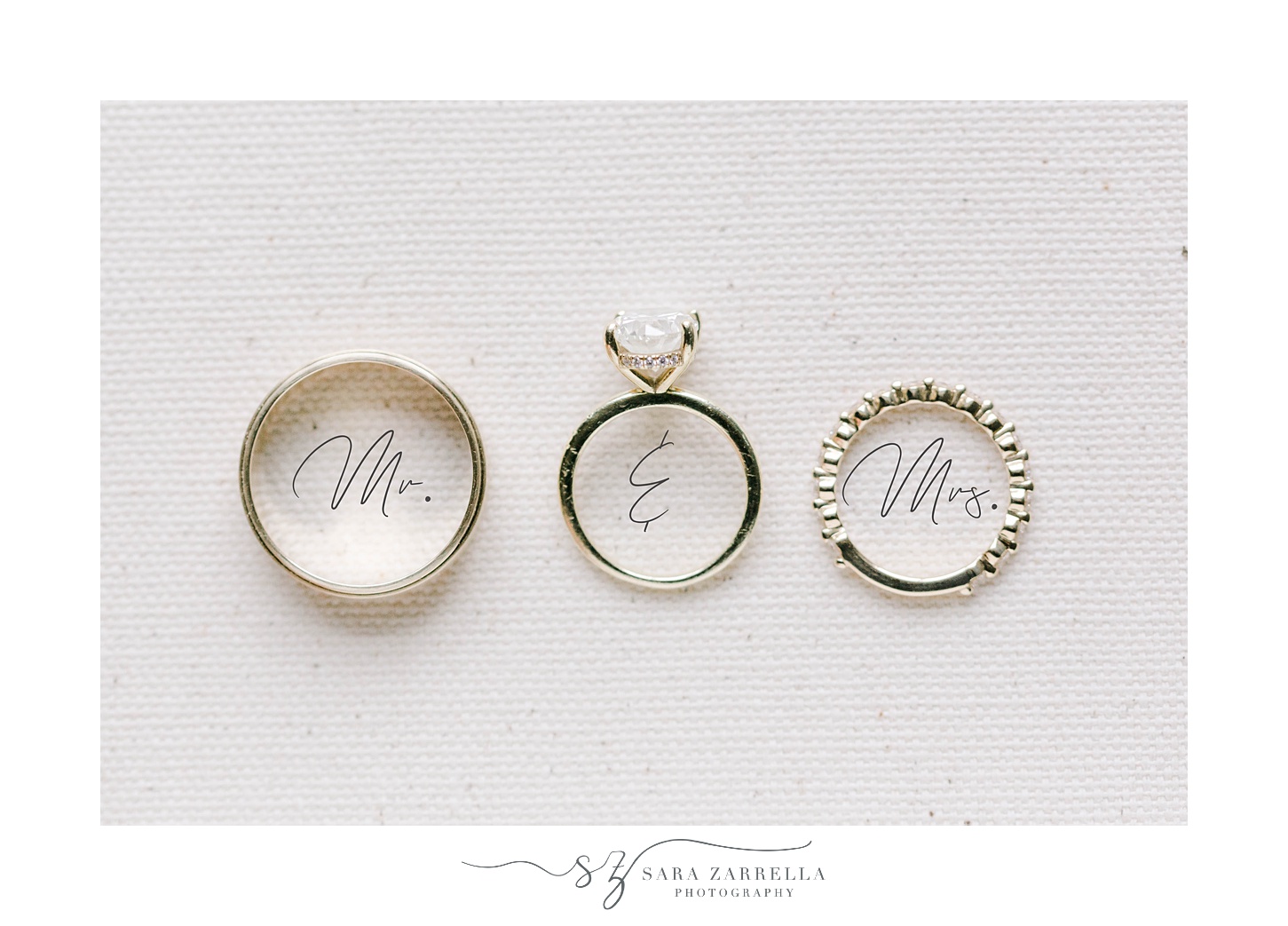 three gold wedding bands rest on Mr and Mrs script