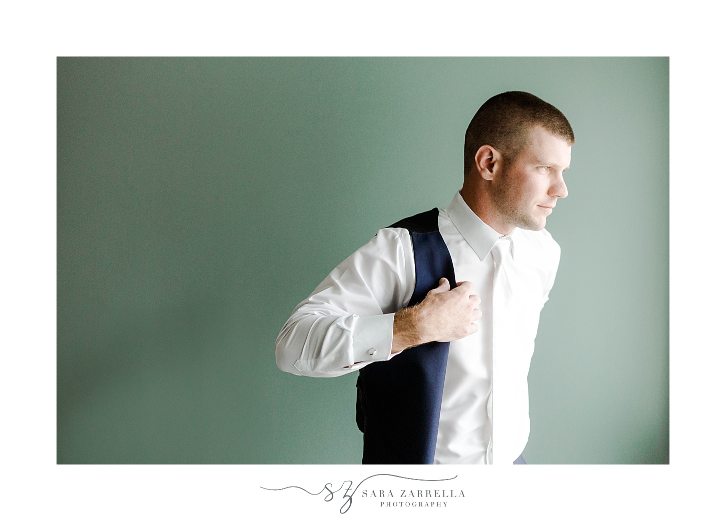 groom puts on navy vest before RI wedding day at the Wyndham Newport Hotel