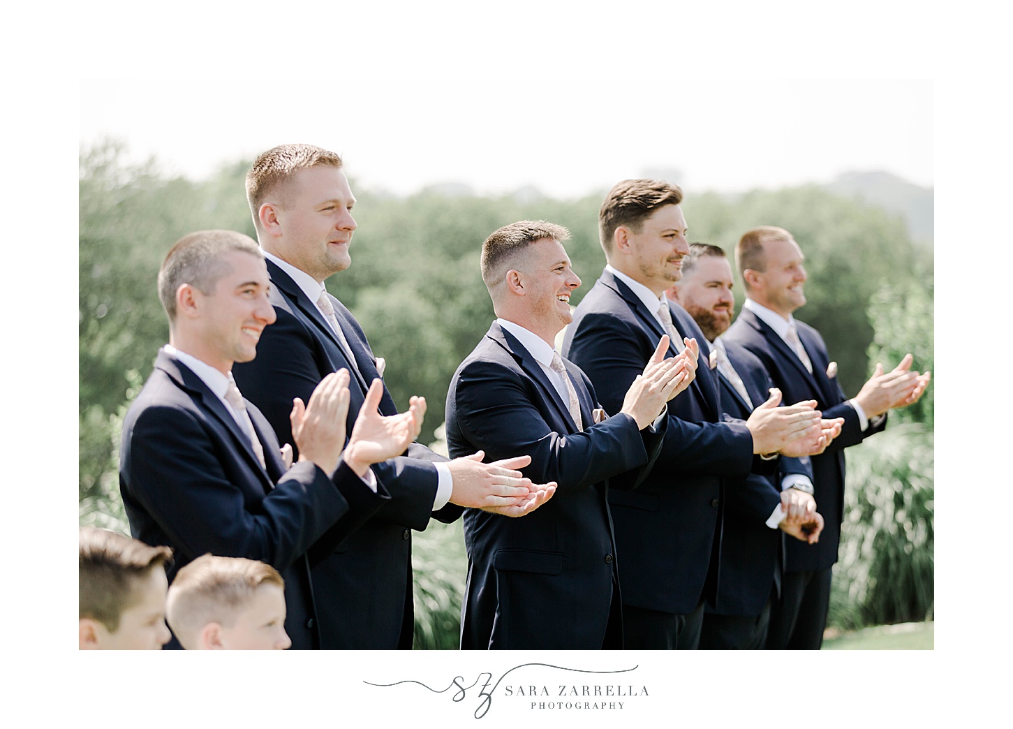 groomsmen in navy suits clap for bride and groom during first look