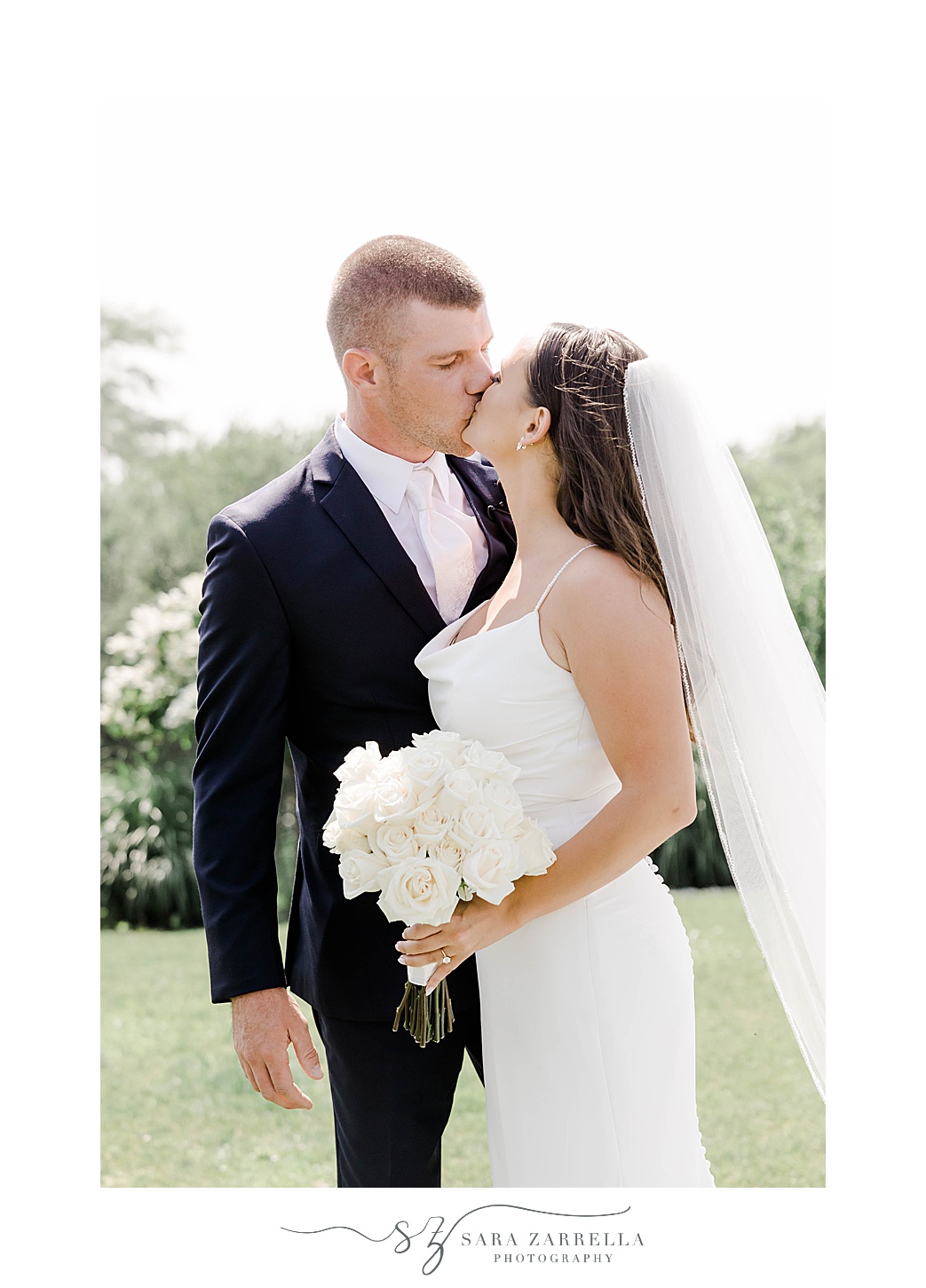 bride and groom kiss while bride holds bouquet of white flowers 