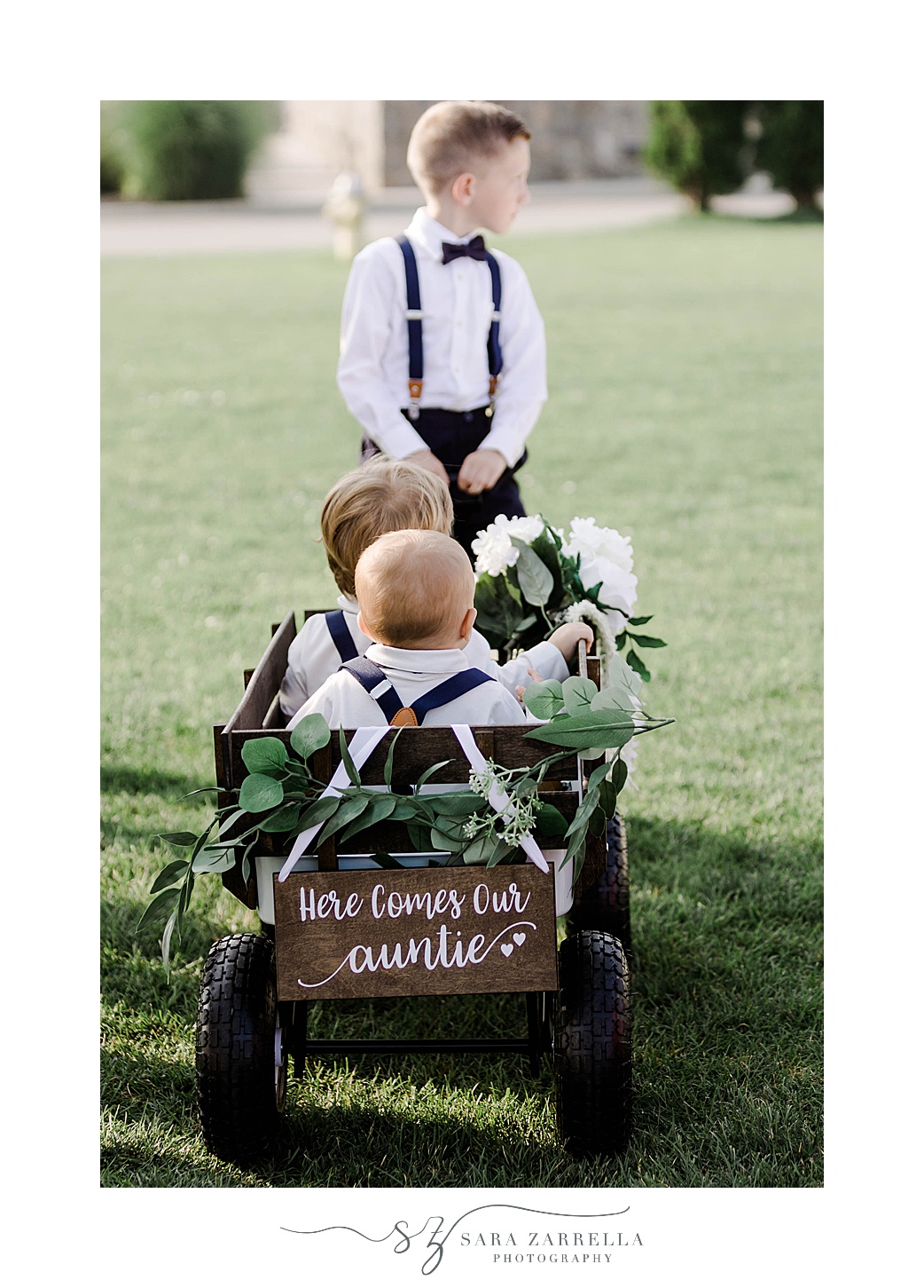 ring bearer pulls brothers down aisle in wagon at the Wyndham Newport Hotel