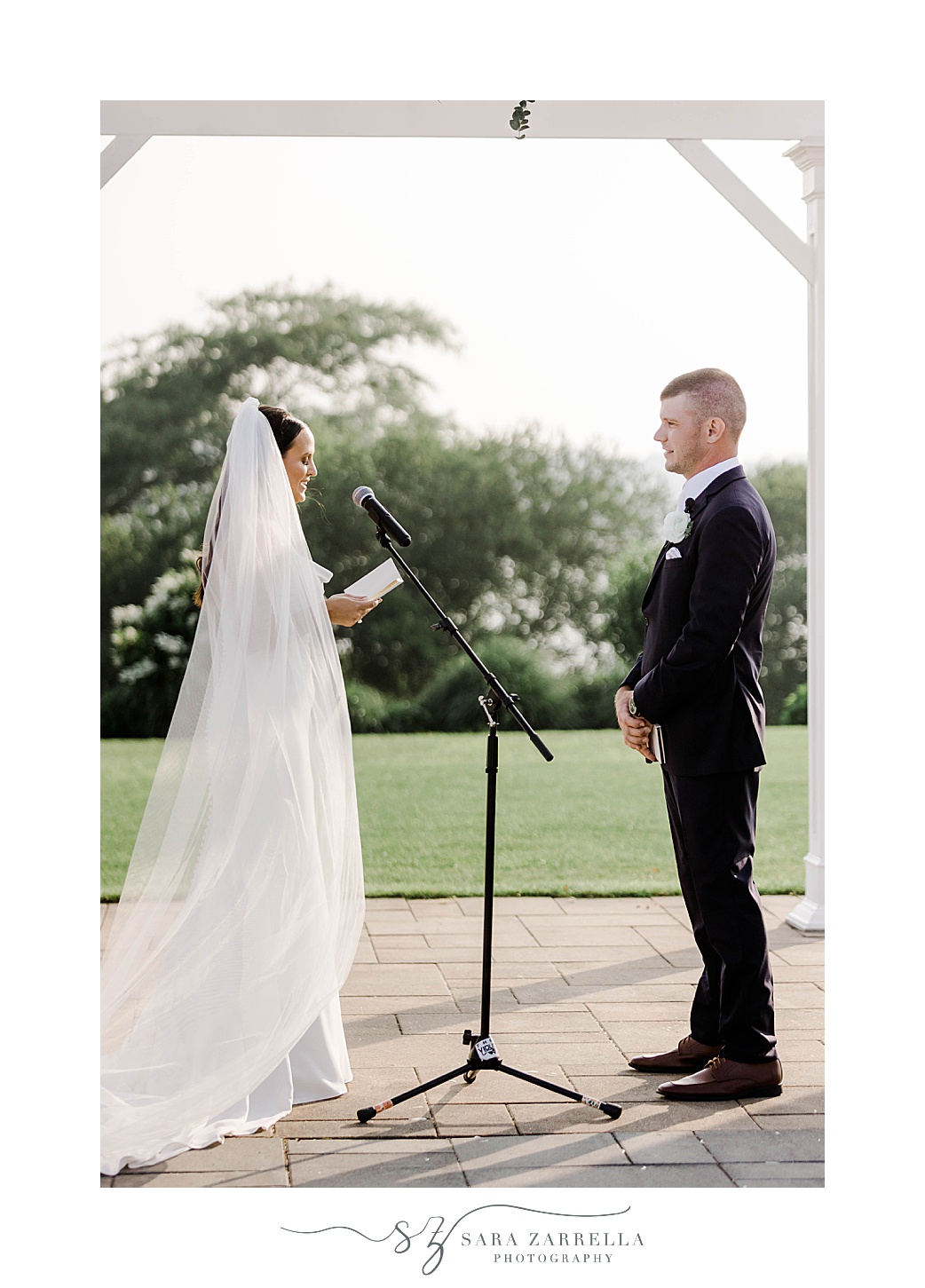 bride reads vows to groom under white arbor in Rhode Island