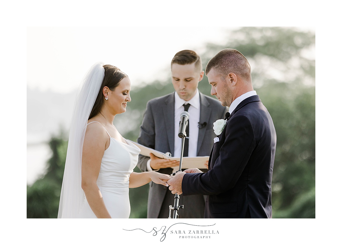 groom puts ring on bride's hand during ceremony at the Wyndham Newport Hotel