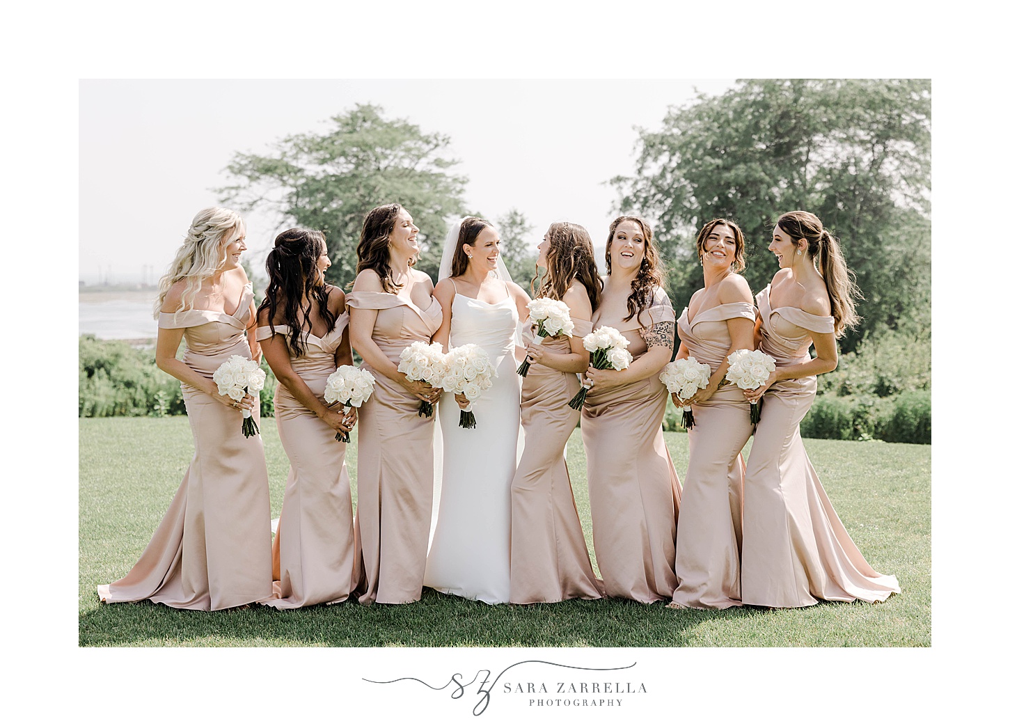 bride smiles at bridesmaid in pink gowns on lawn at the Wyndham Newport Hotel