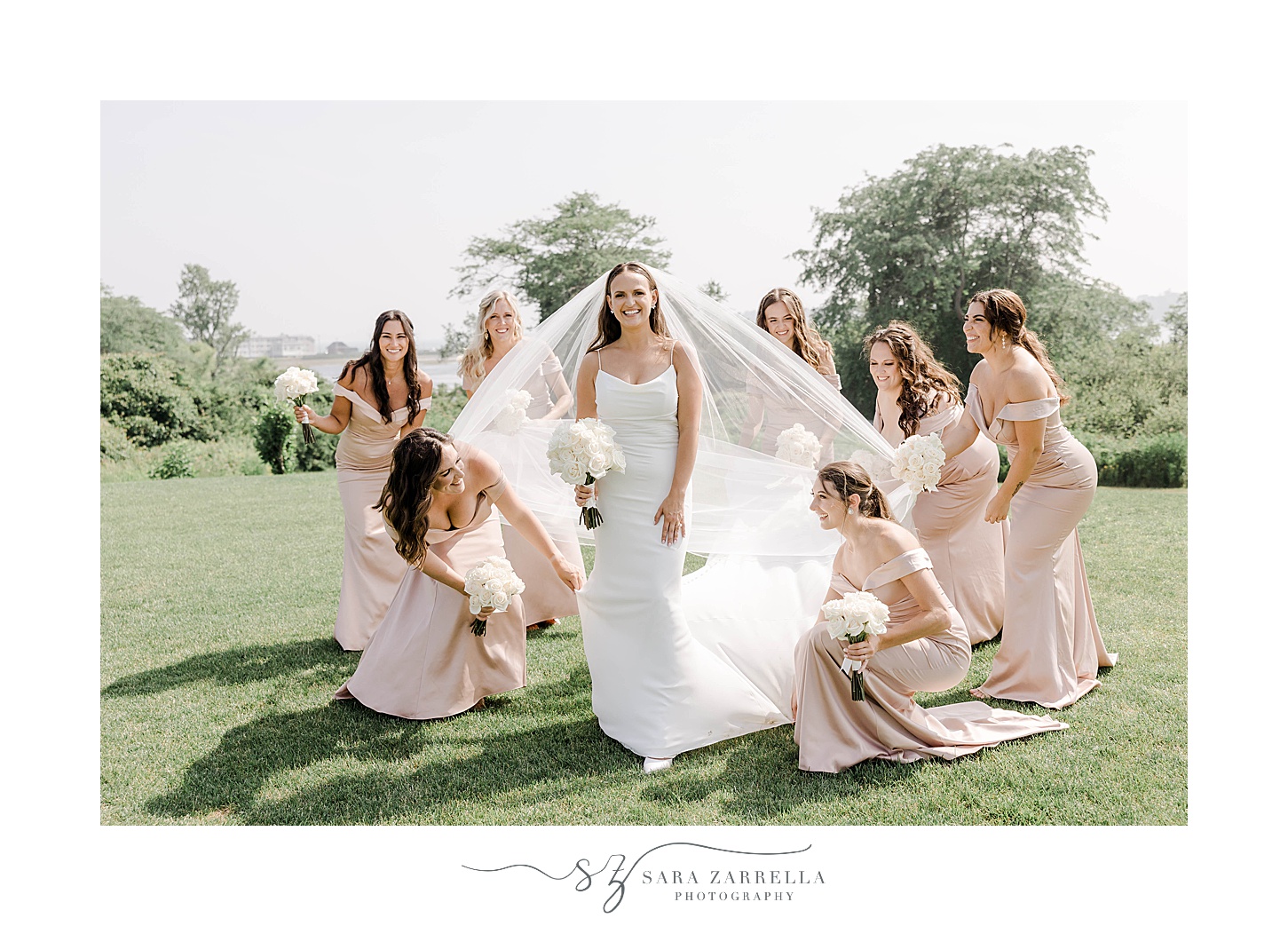 bridesmaids in pink gowns help bride adjust veil on lawn at the Wyndham Newport Hotel
