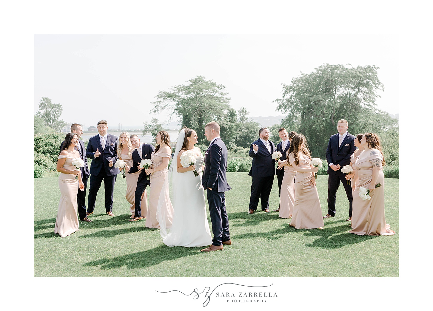 newlyweds hug in front of wedding party on lawn at the Wyndham Newport Hotel