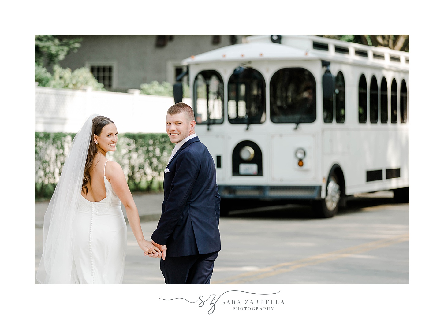 newlyweds hold hands turning around from white trolley 