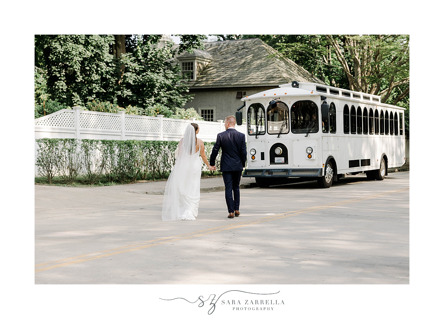 newlyweds walk towards white trolley while holding hands in Newport RI
