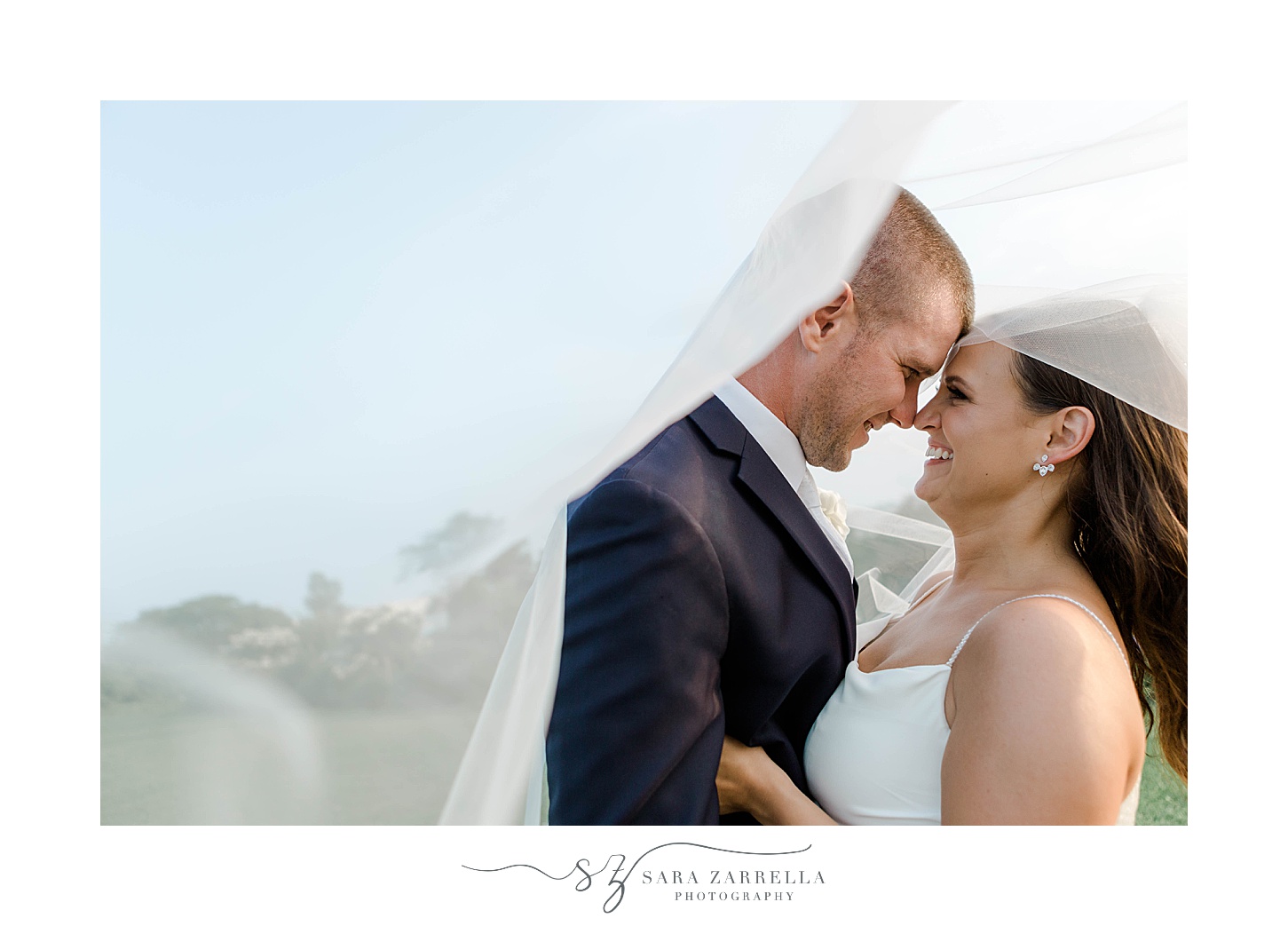 newlyweds lean for a kiss under bride's veil in Newport RI