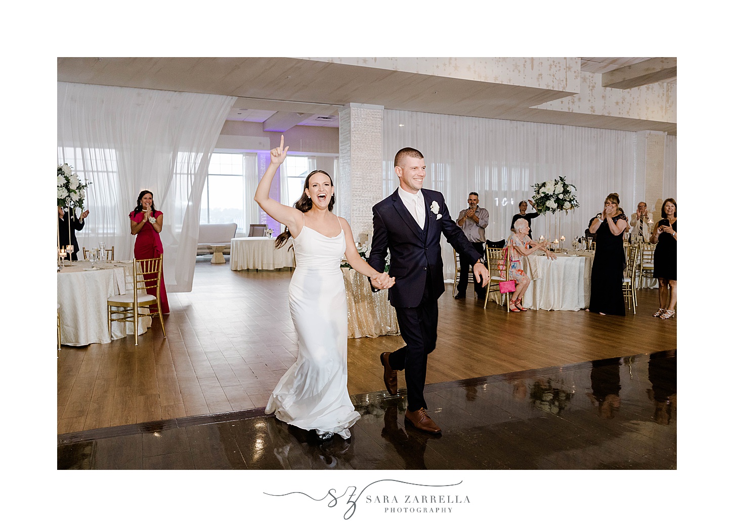 bride and groom hold hands cheering walking into the Wyndham Newport Hotel wedding reception 