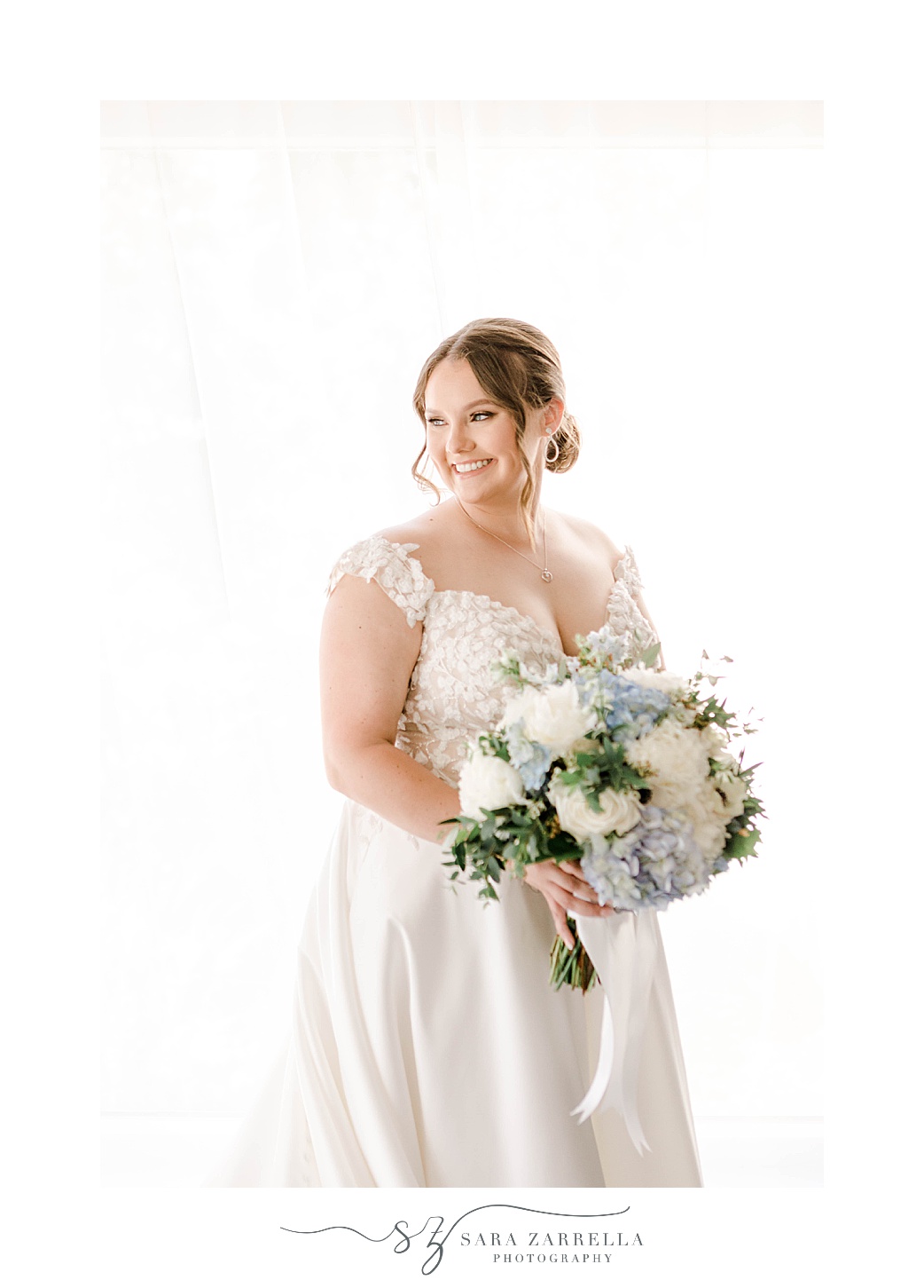 bride smiles looking over shoulder in wedding gown with pastel blue and white flowers 