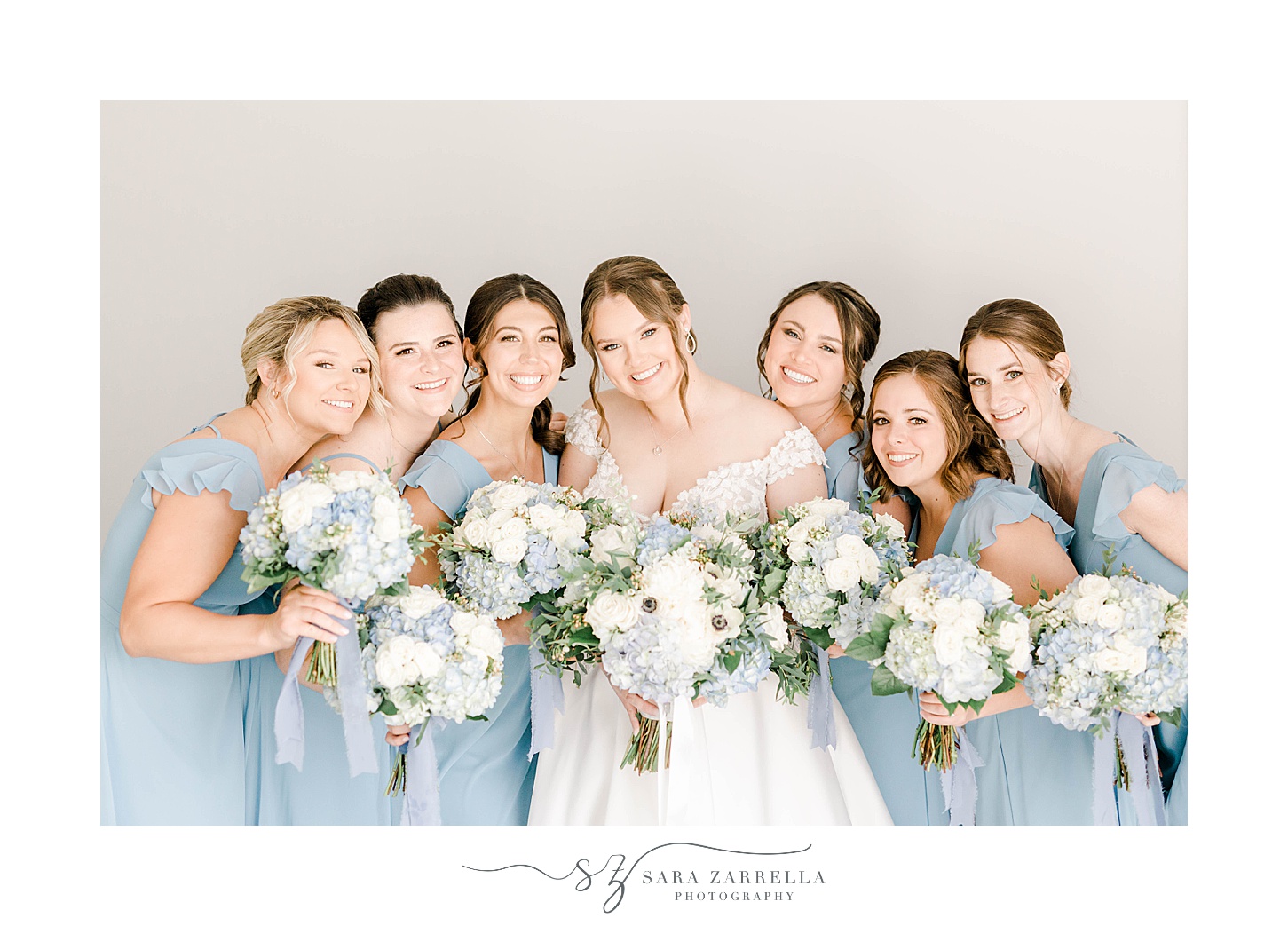 bridesmaids in light blue gowns hug bride at Newport Harbor Island Resort