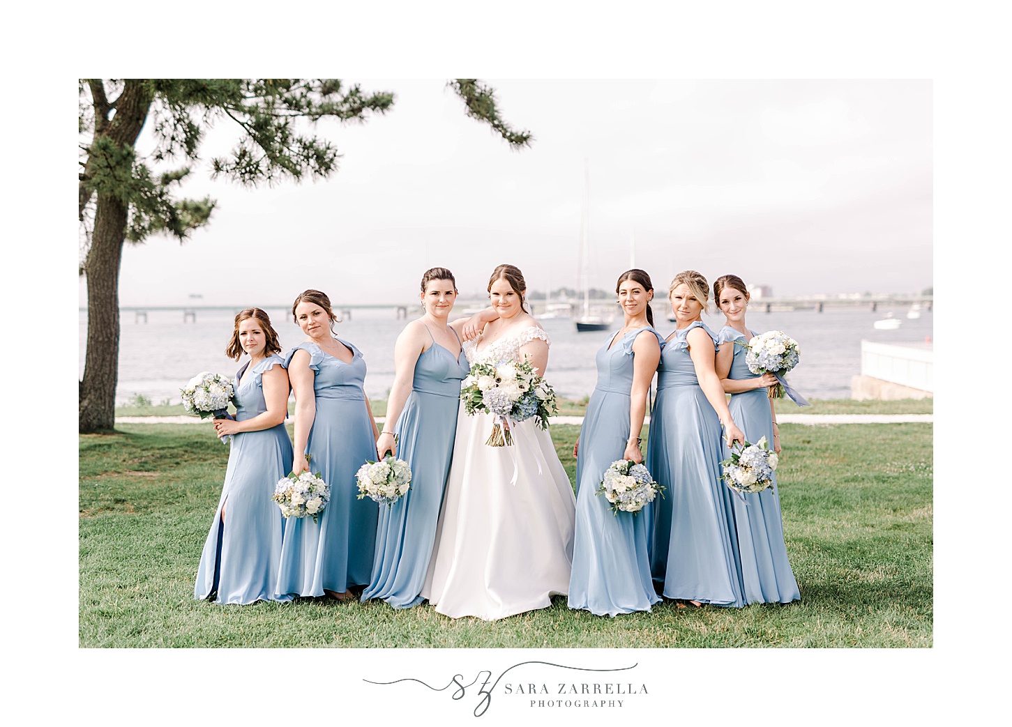 bride poses with bridesmaids in light blue dress before Newport Harbor Island Resort wedding