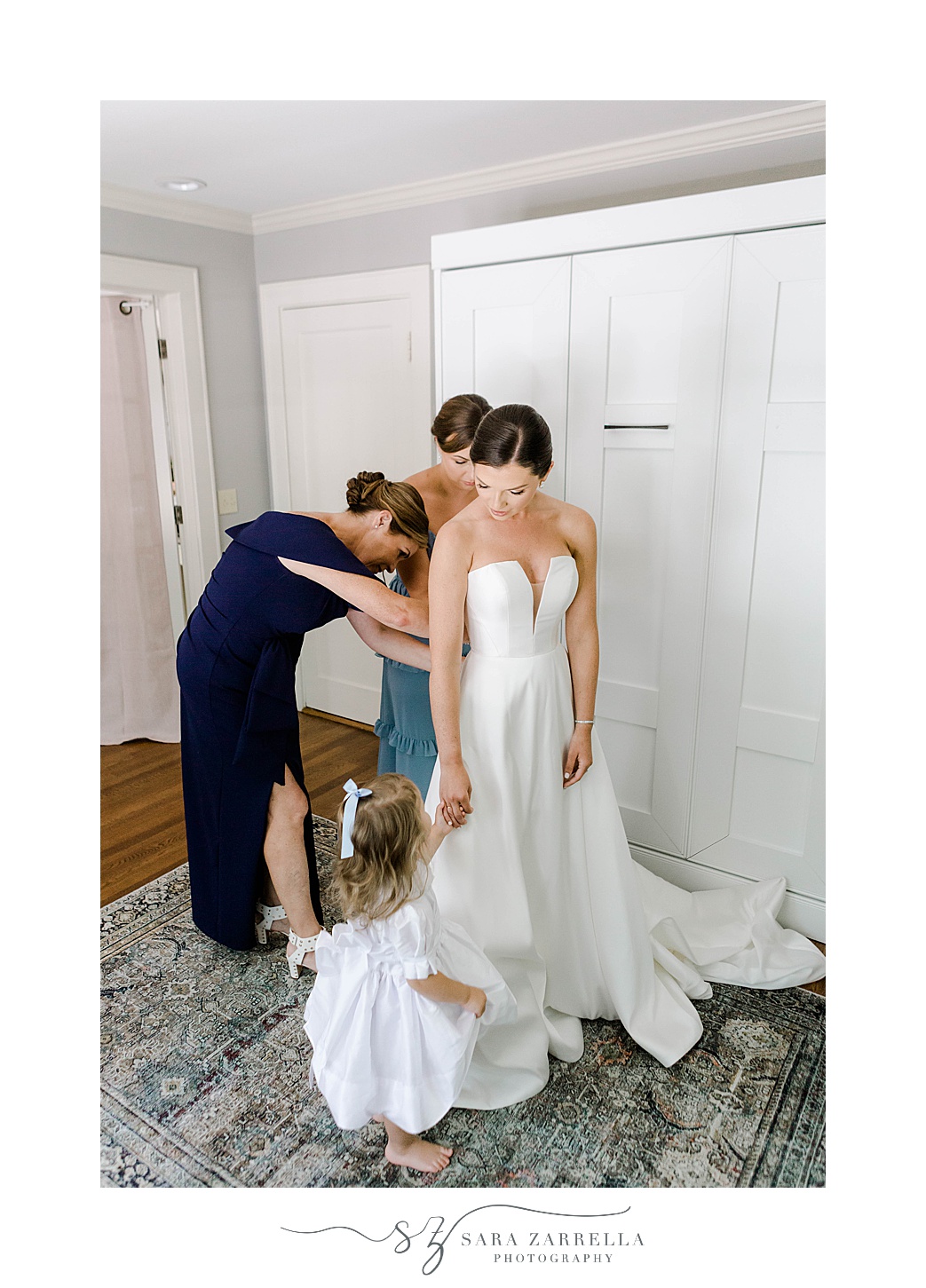 bridesmaid and mother help bride into wedding dress at Regatta Place