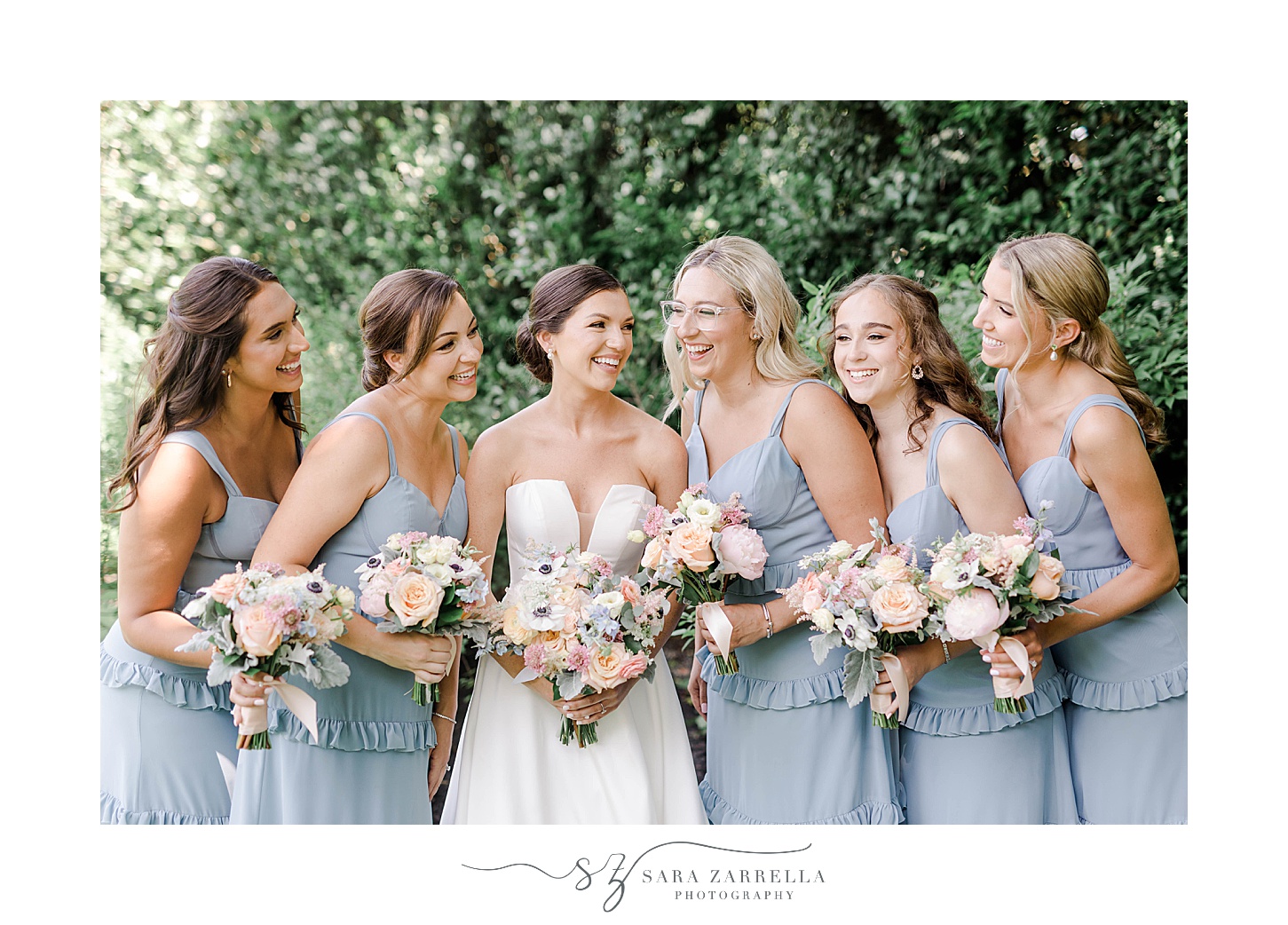 bride poses with bridesmaids in light blue gowns at Ochre Place