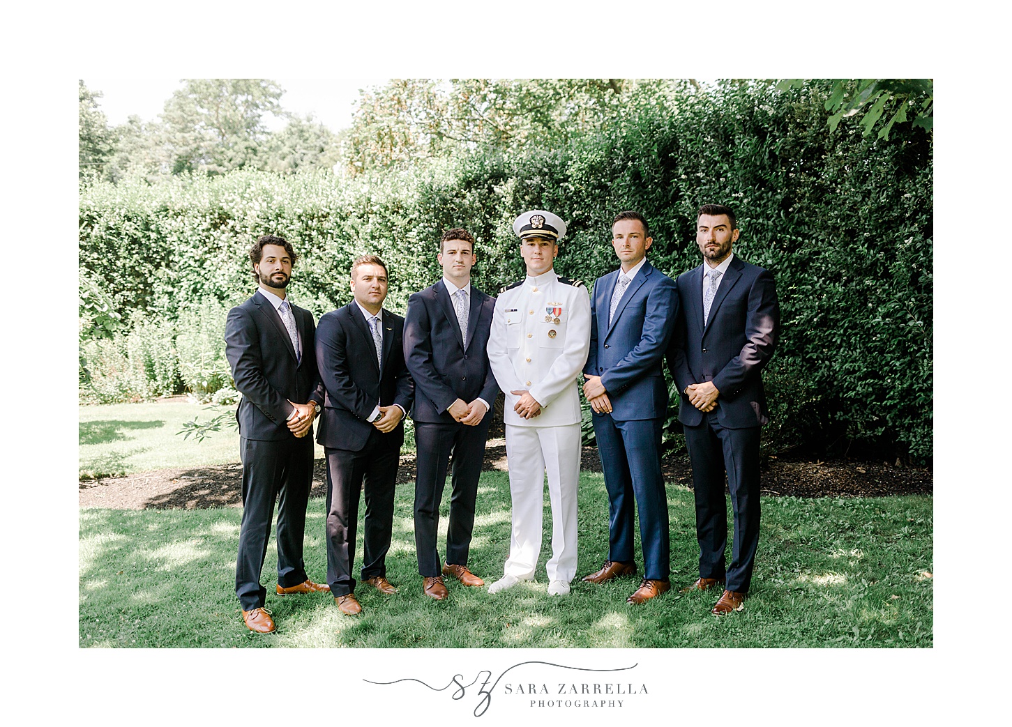 groom in white uniform poses with groomsmen in blue suits at Ochre Place