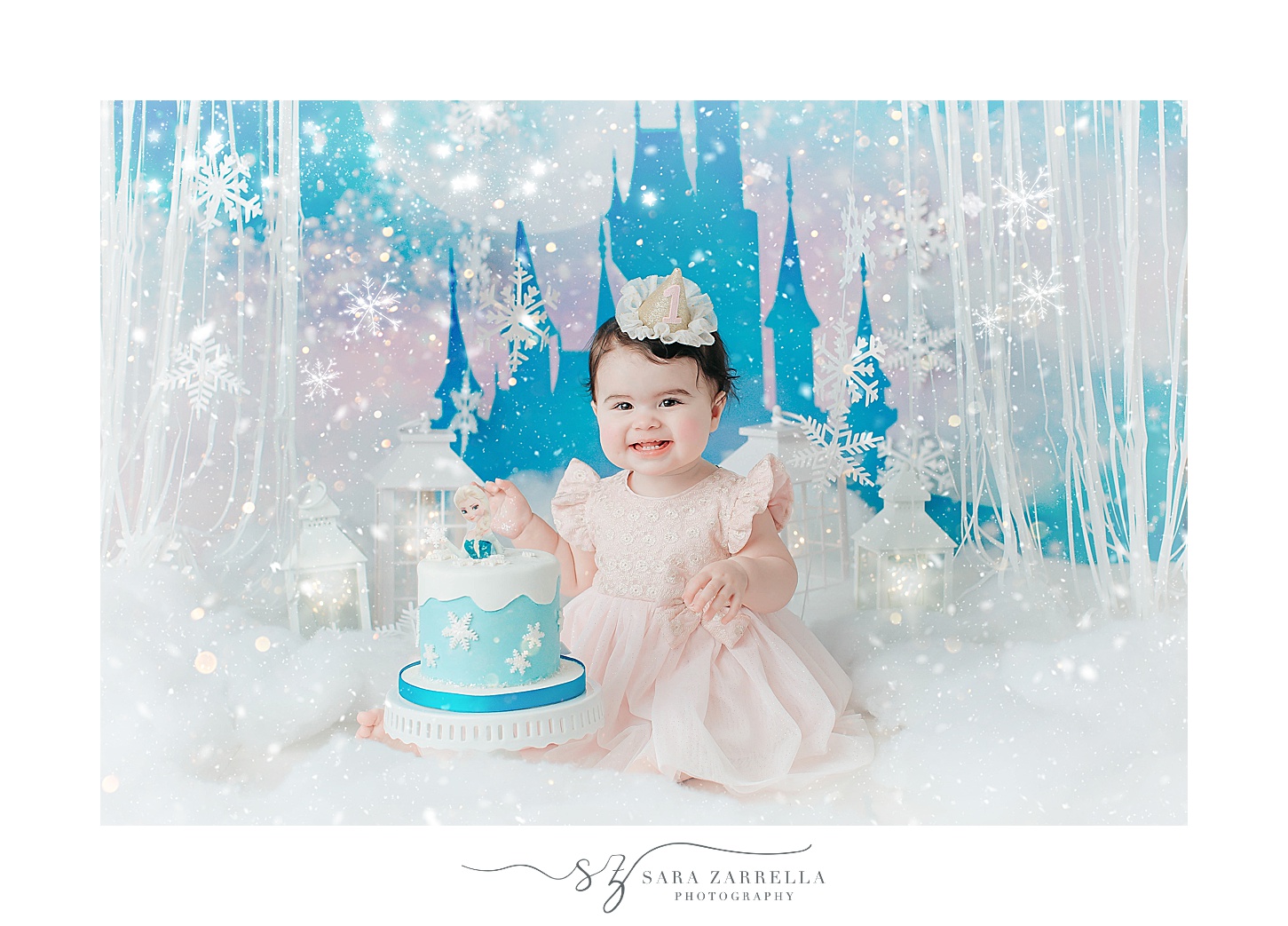 baby girl sits in front of castle and winter wonderland setup for cake smash portraits with Sara Zarrella Photography