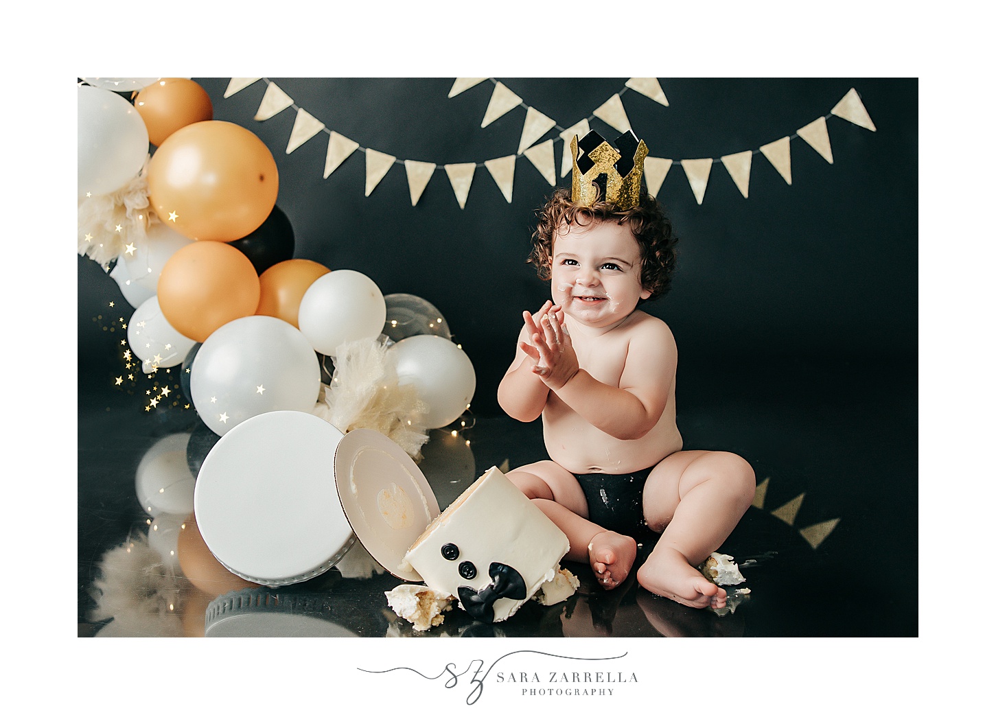boy claps as cake falls off stand during cake smash portraits with Sara Zarrella Photography 