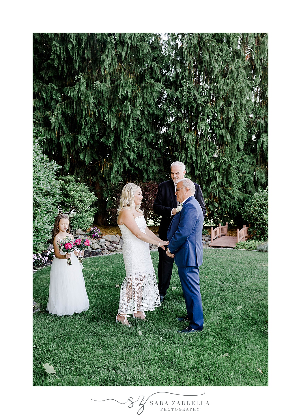 bride and groom hold hands while flower girl daughter stands by them 