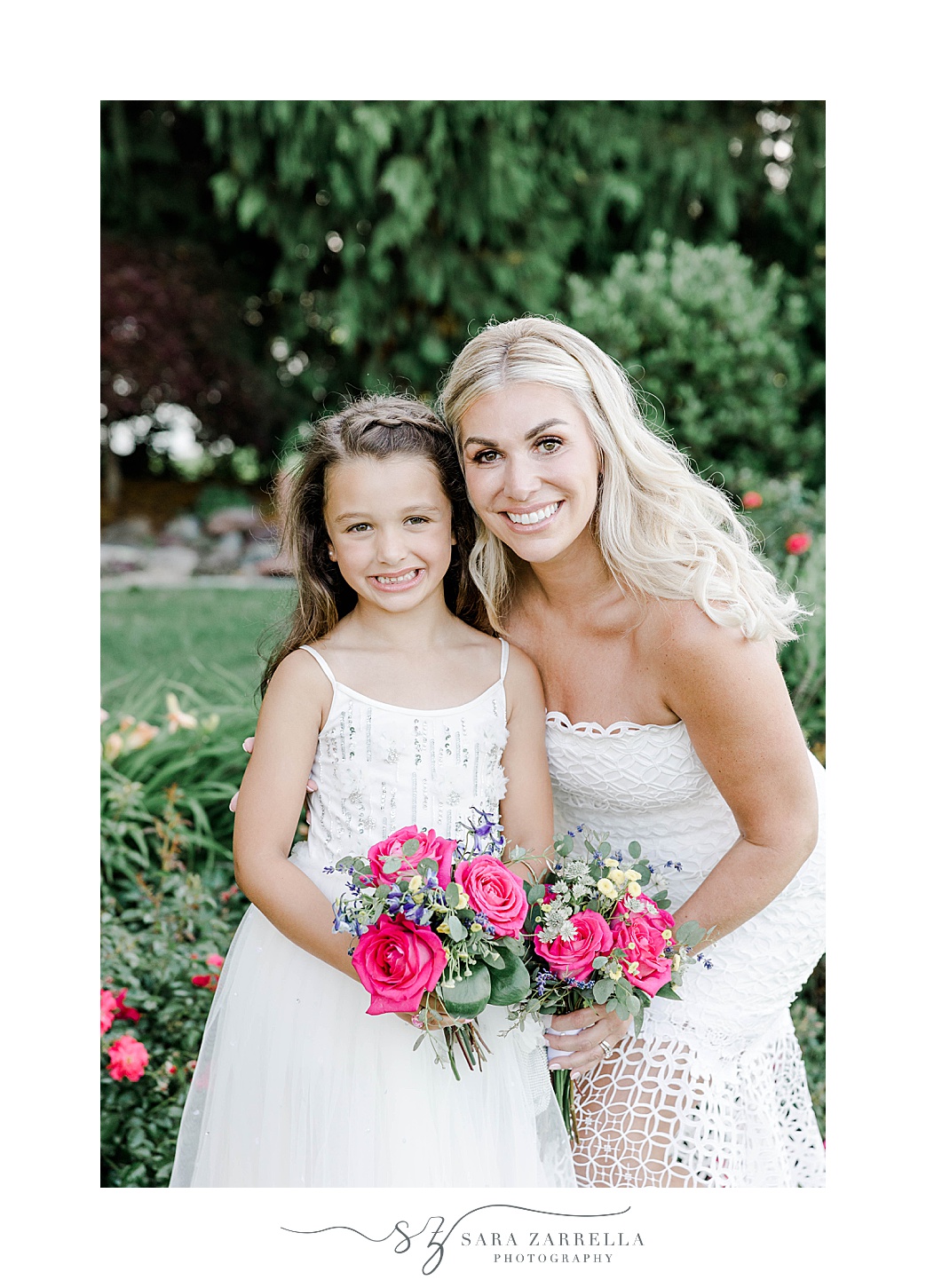 bride hugs flower girl in front of bushes at Kirkbrae Country Club