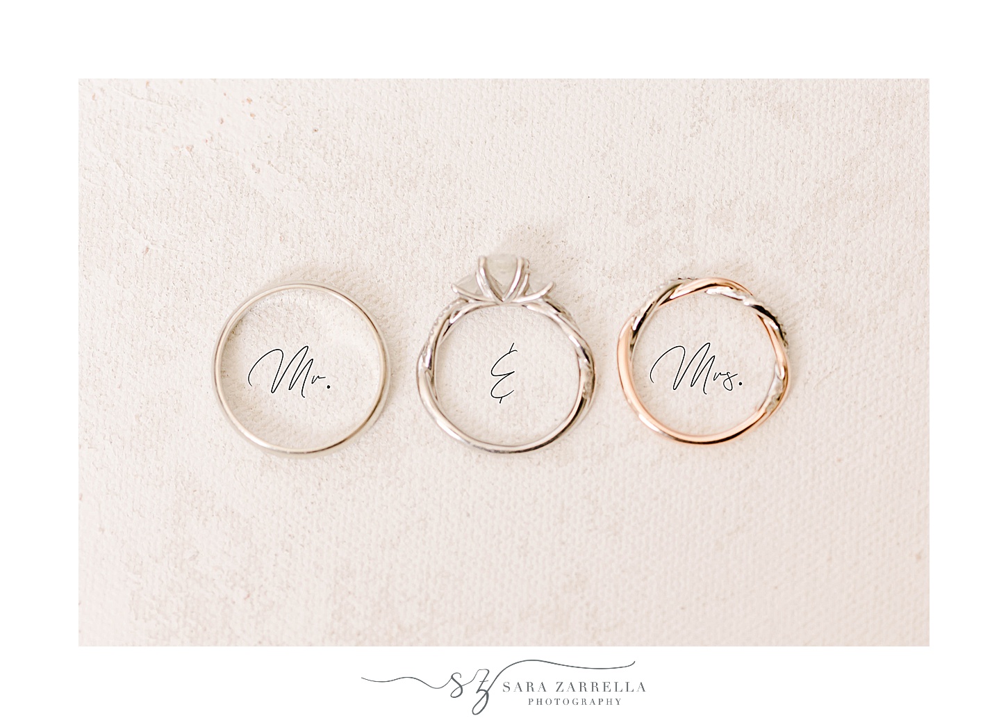 three wedding rings lay over Mr and Mrs script 