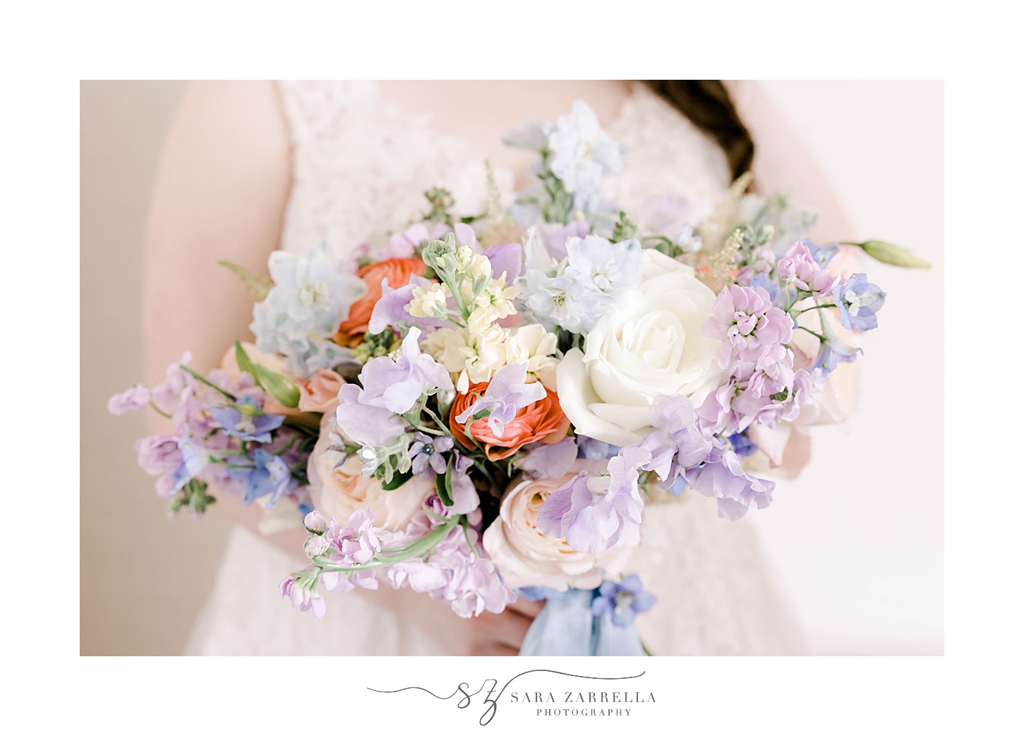 bride holds bouquet of white flowers and pastel accents 