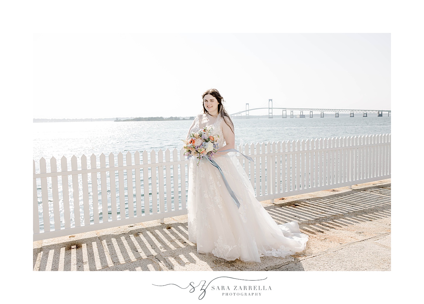 bride poses along white fence in Newport RI