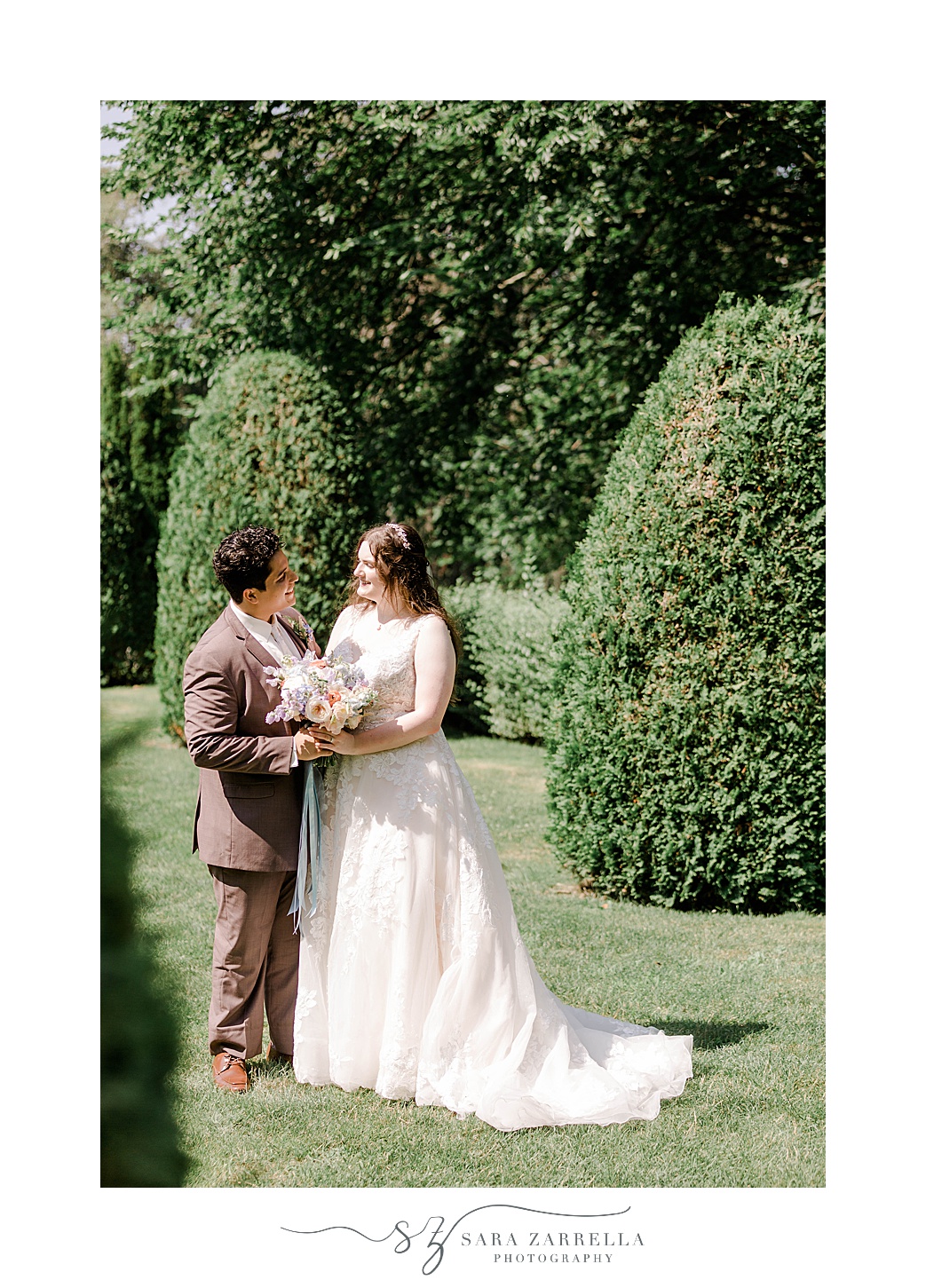 bride and groom hug between hedges at the Elms in Newport RI