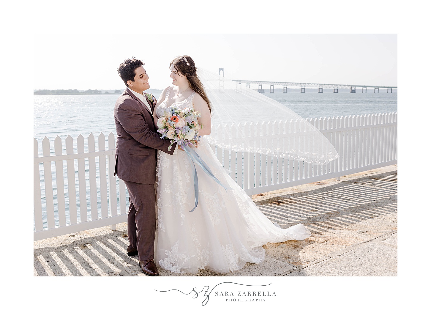 bride and groom hug against the white fence at Newport Harbor Island Resort